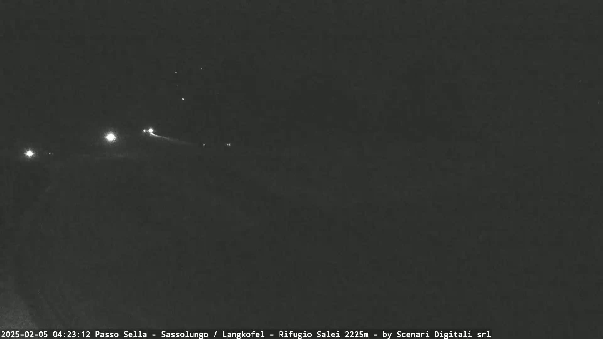 At night, several distant lights are visible in the darkness.