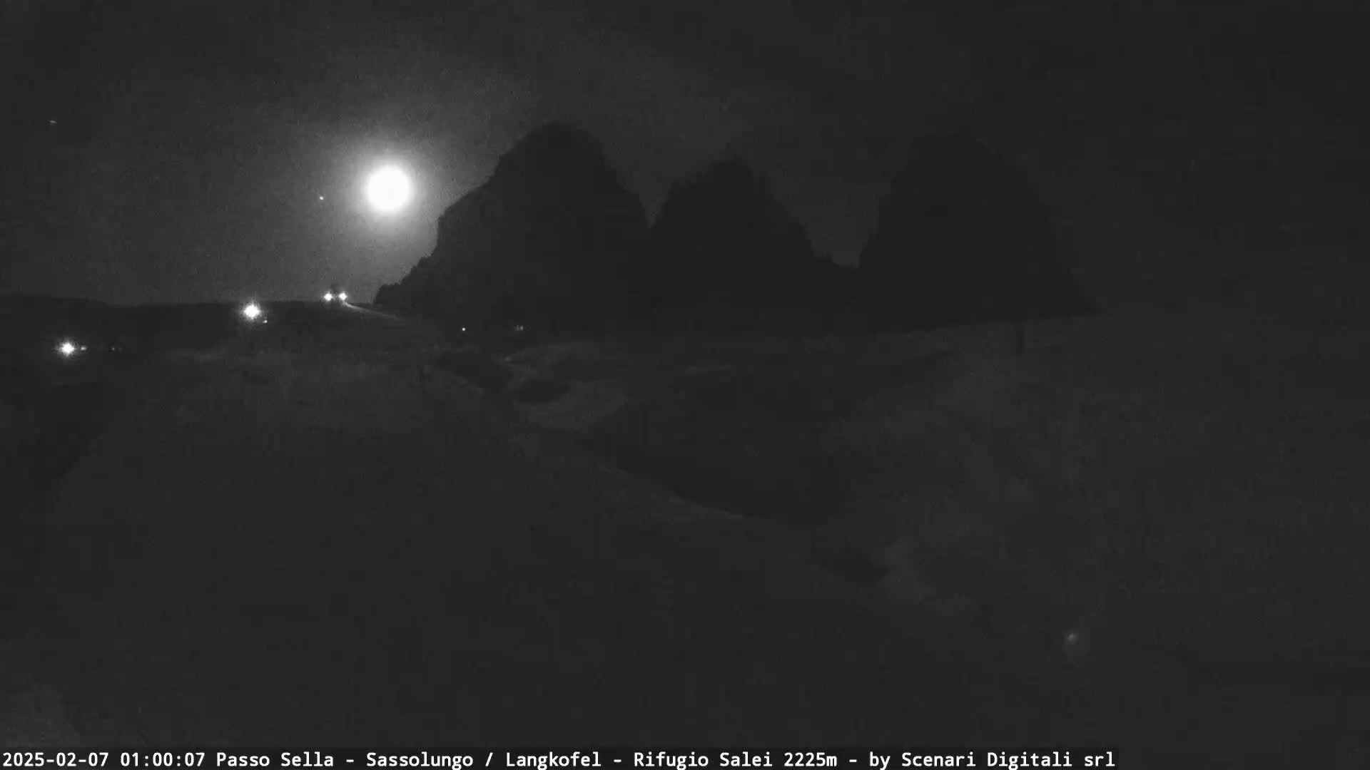 A nighttime scene of a snow-covered landscape with mountains in the background under a bright moon.