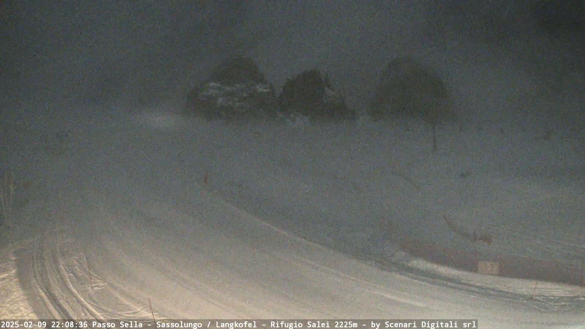 A snow-covered landscape at night is obscured by blowing snow.