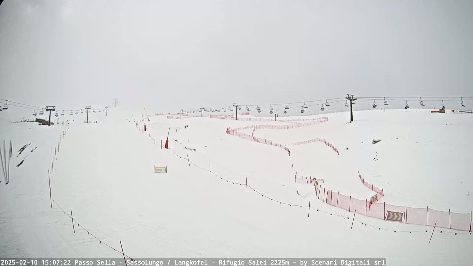 A snowy ski slope with a chairlift and red safety nets is visible in foggy conditions.