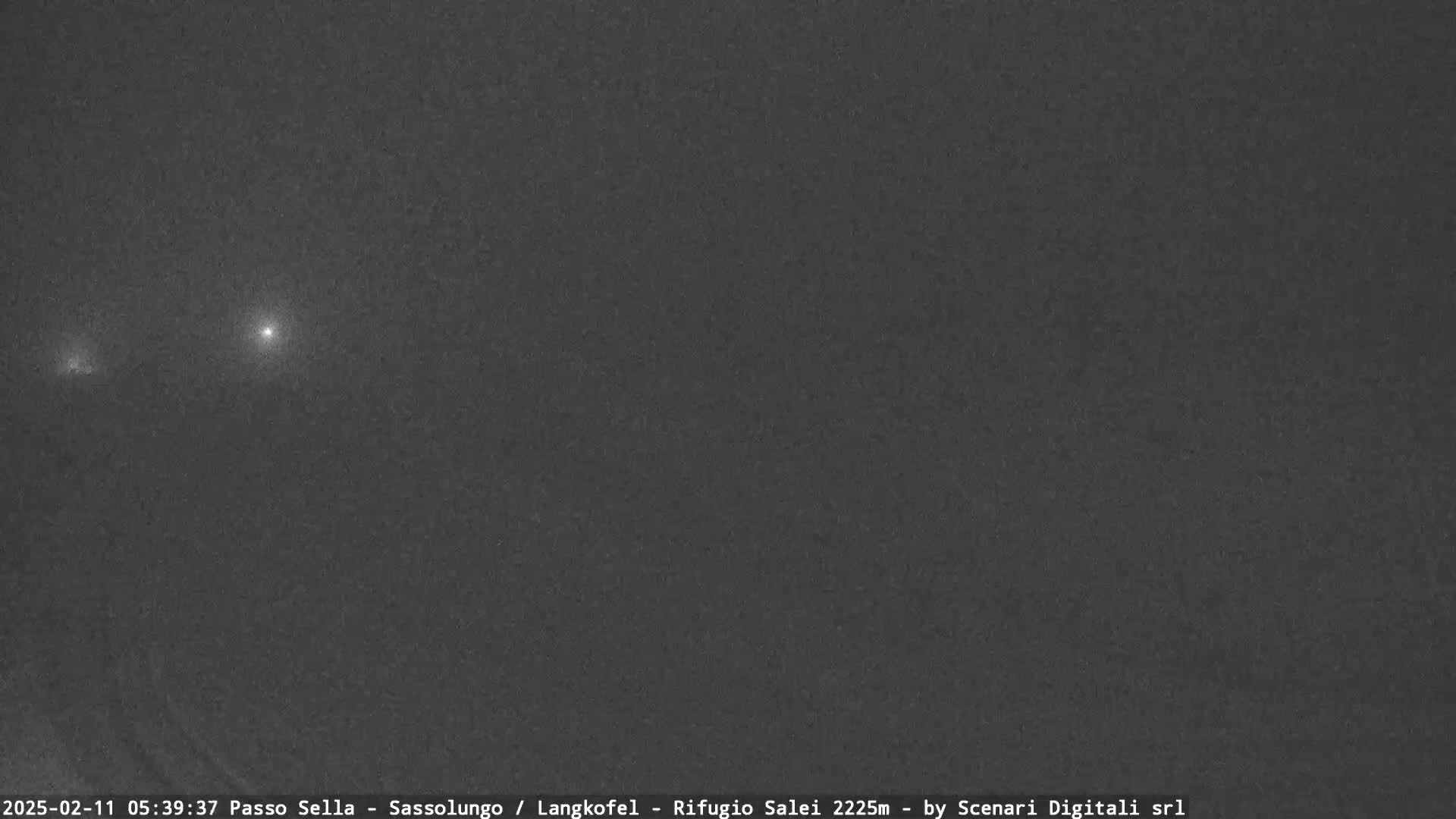 A dark, nighttime scene shows two distant points of light in a dark, overcast sky.