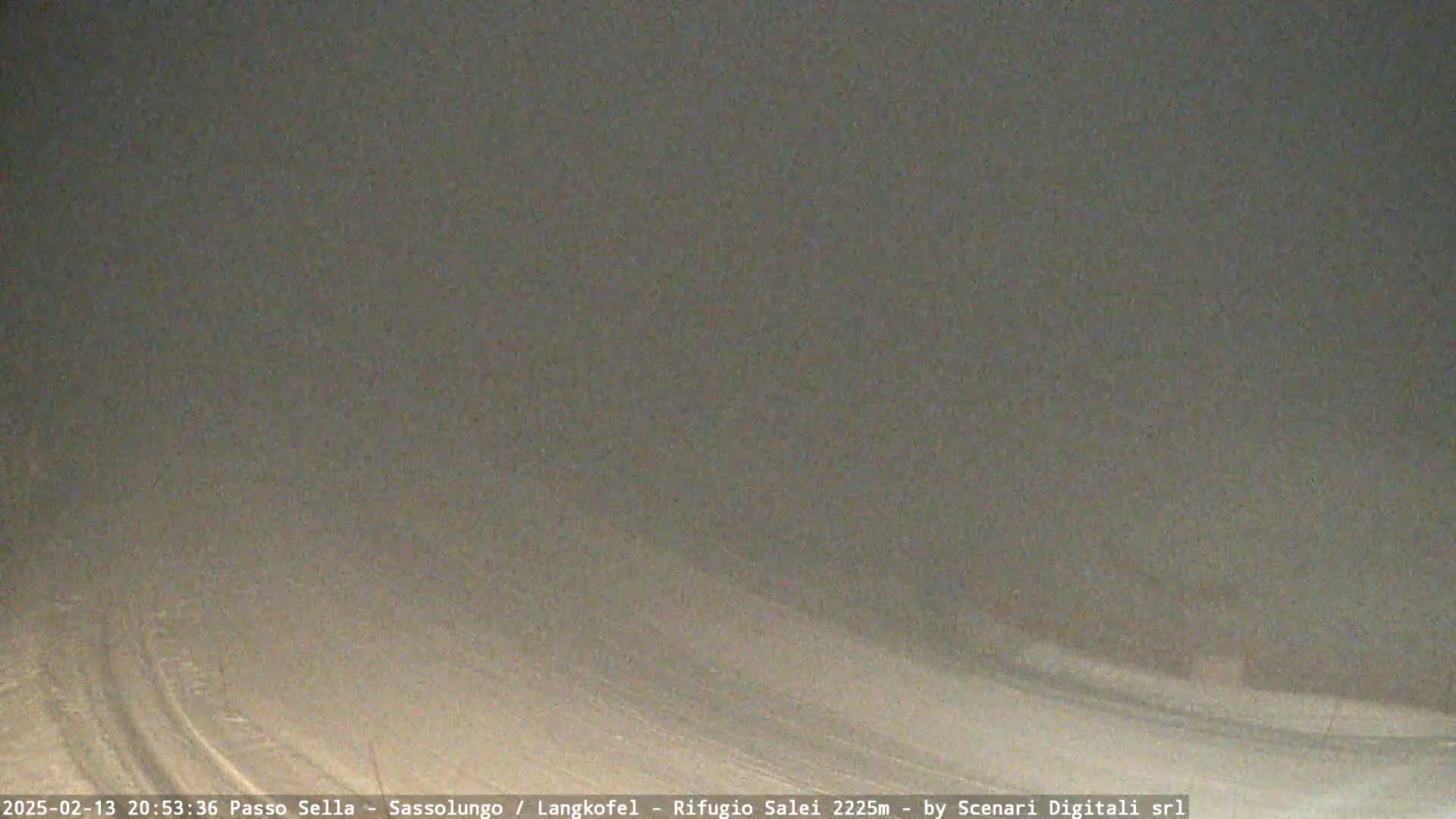 A snow-covered, gently sloping landscape is shrouded in heavy fog or blowing snow at night.