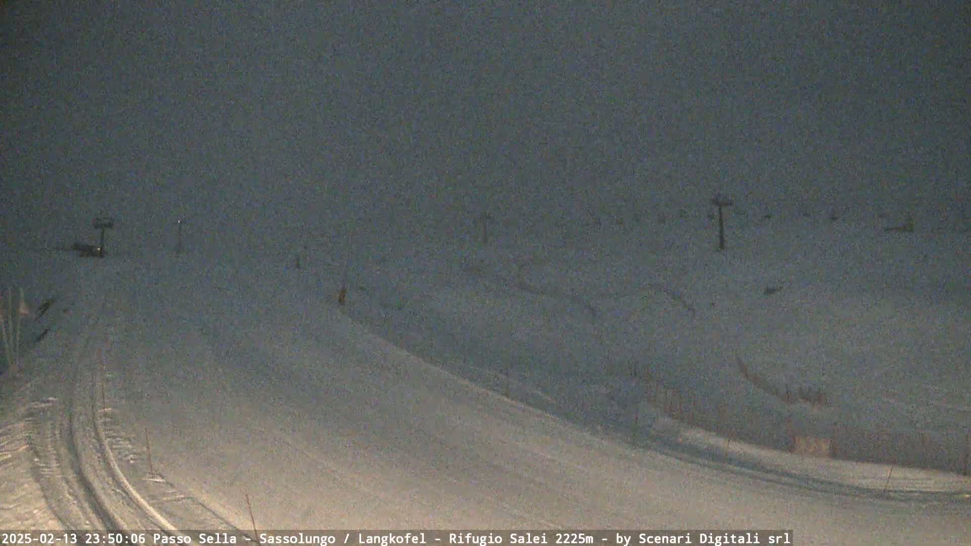 A snow-covered ski slope is visible under a dark, overcast sky at night.