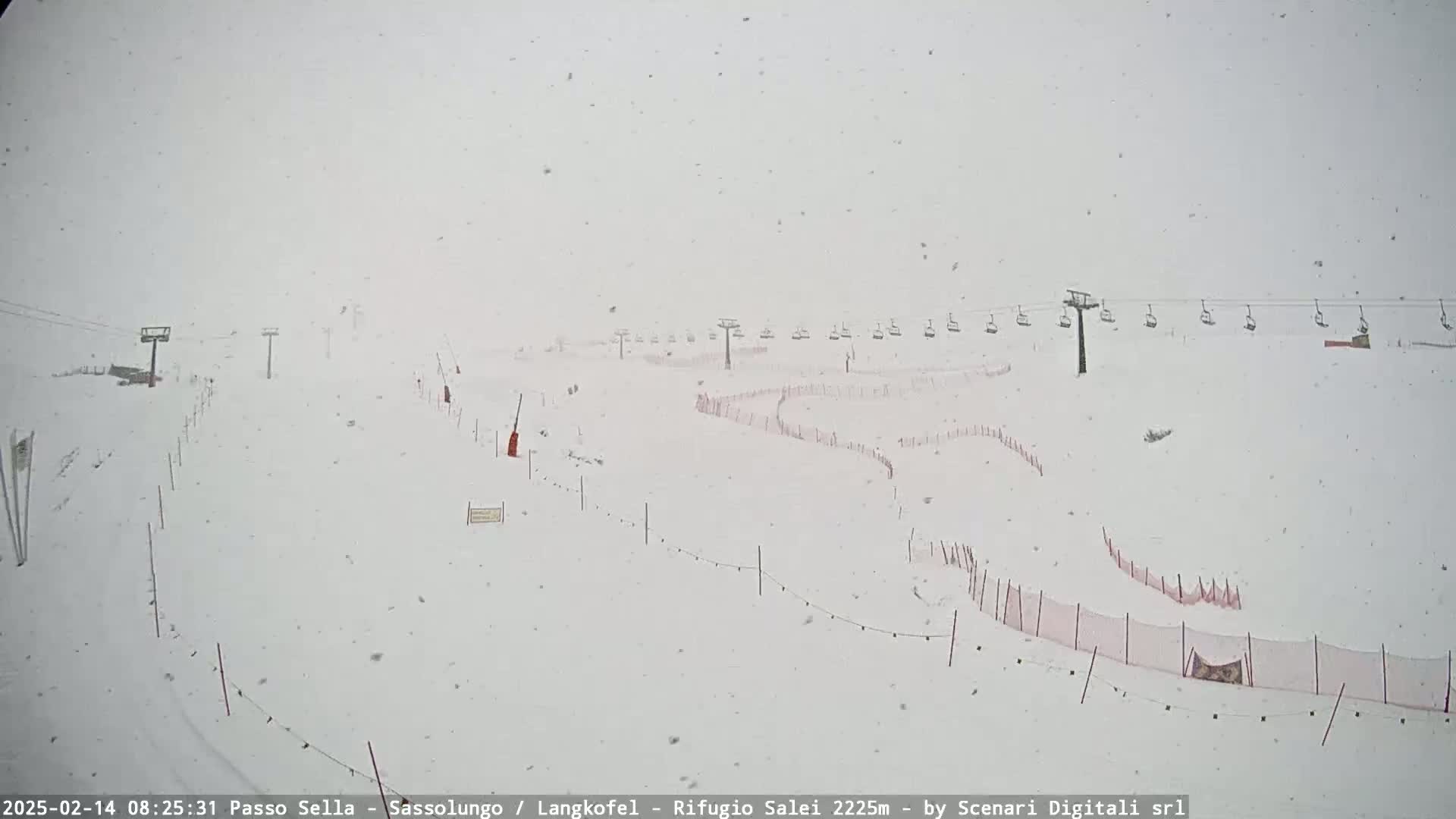 A snow-covered ski slope with chairlifts and safety nets is visible during a heavy snowfall.