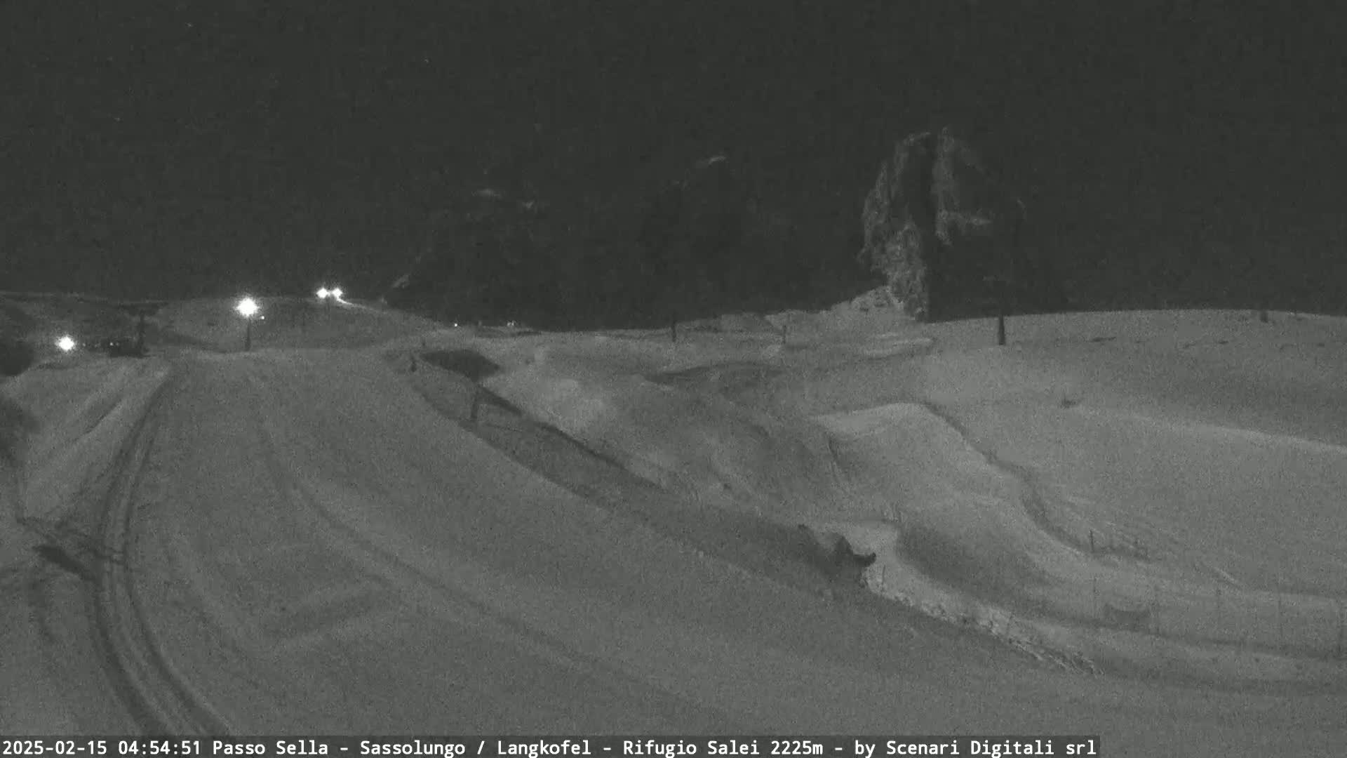 A snow-covered landscape is visible at night, illuminated by a few distant lights.