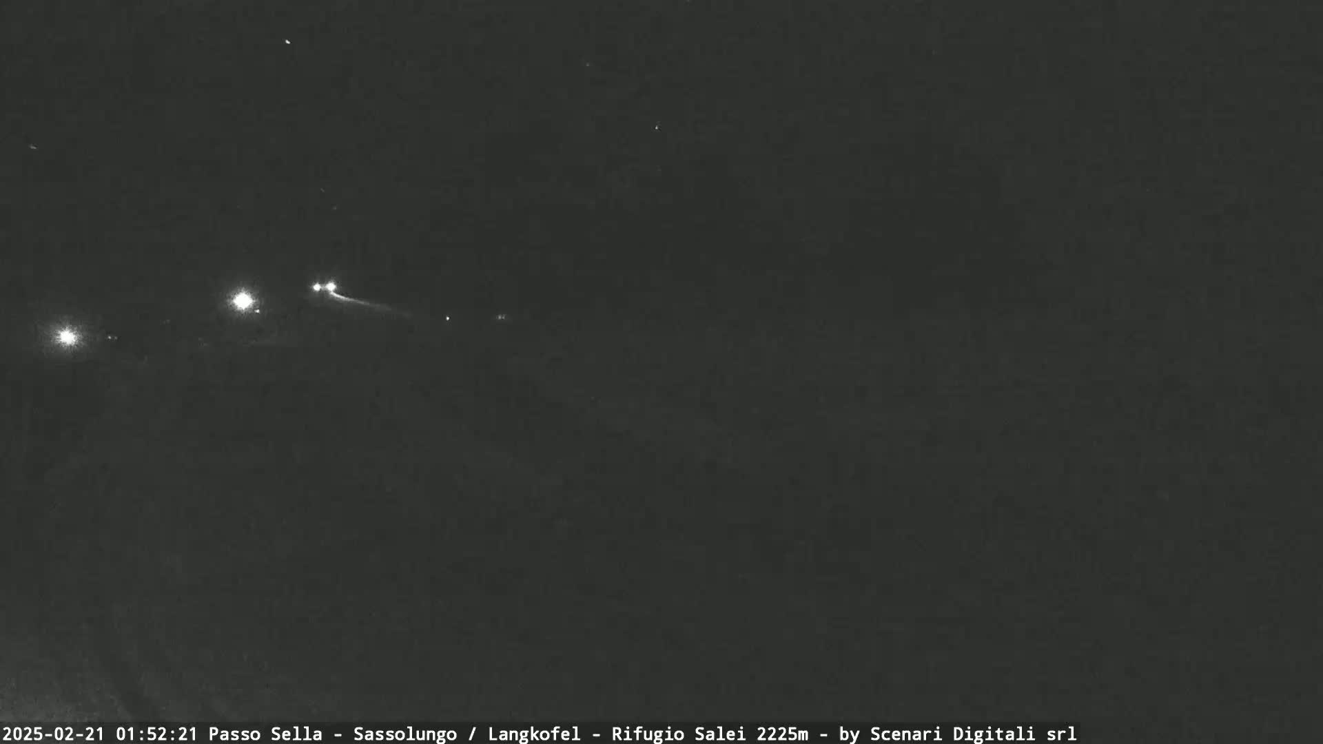 A nighttime long-exposure shot shows several distant headlights on a dark road under a clear, starlit sky.