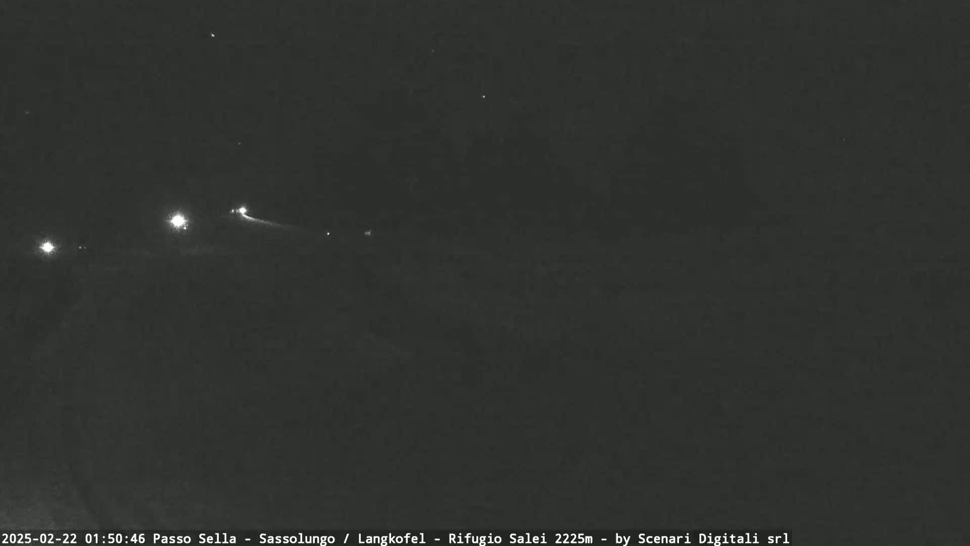 A nighttime, long-range view shows a dark landscape with a few distant lights visible.