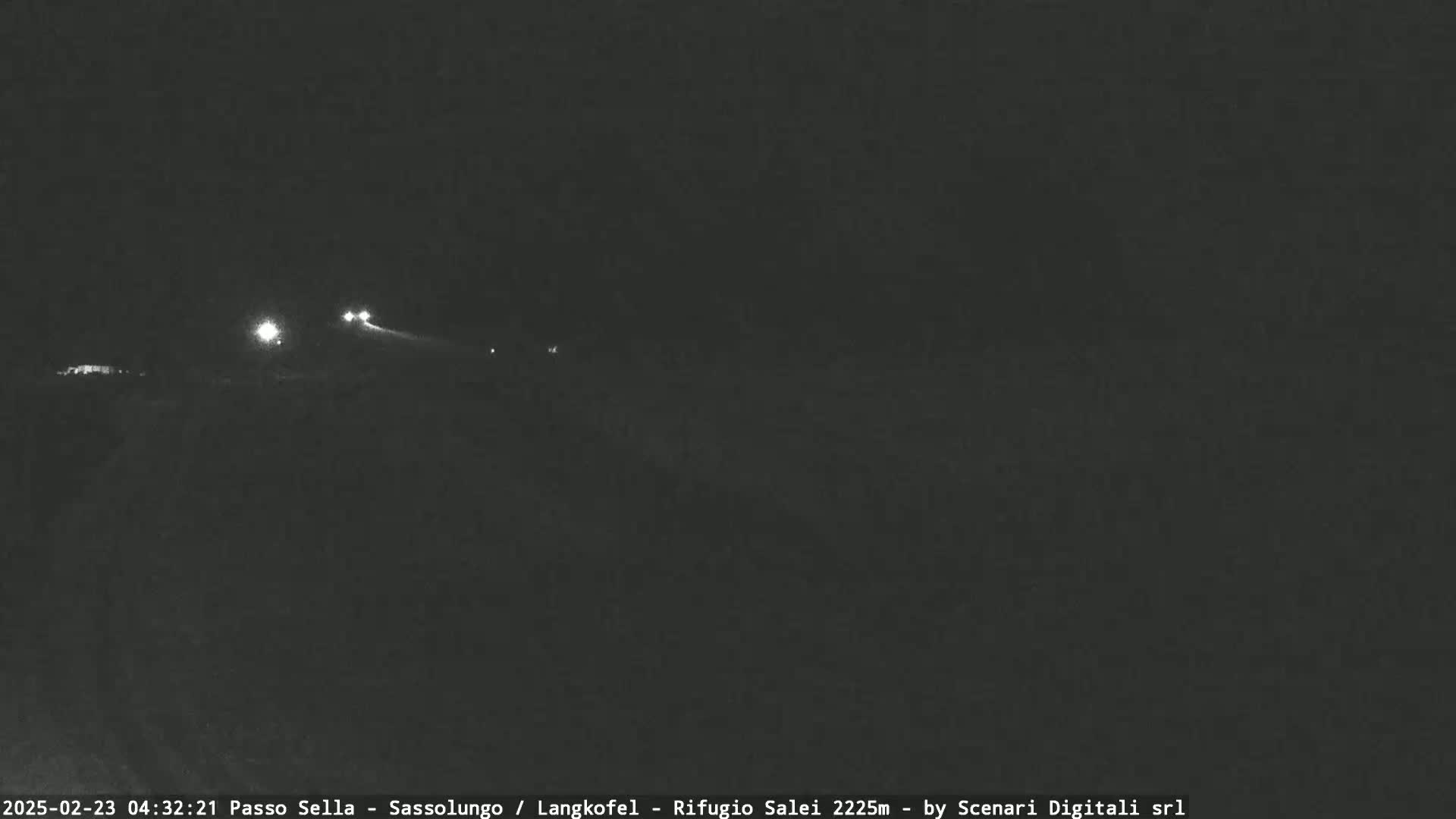 At night, vehicle headlights are visible in the distance on a dark road.