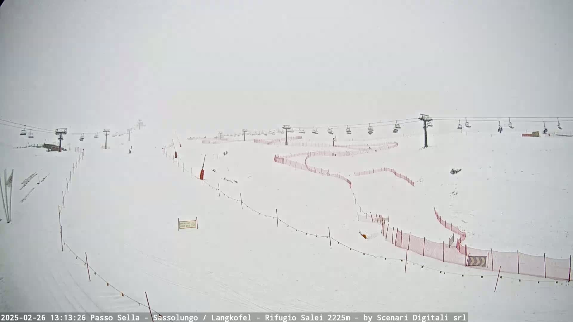 A snowy ski slope with several chairlifts and red safety nets is visible in heavy snow.