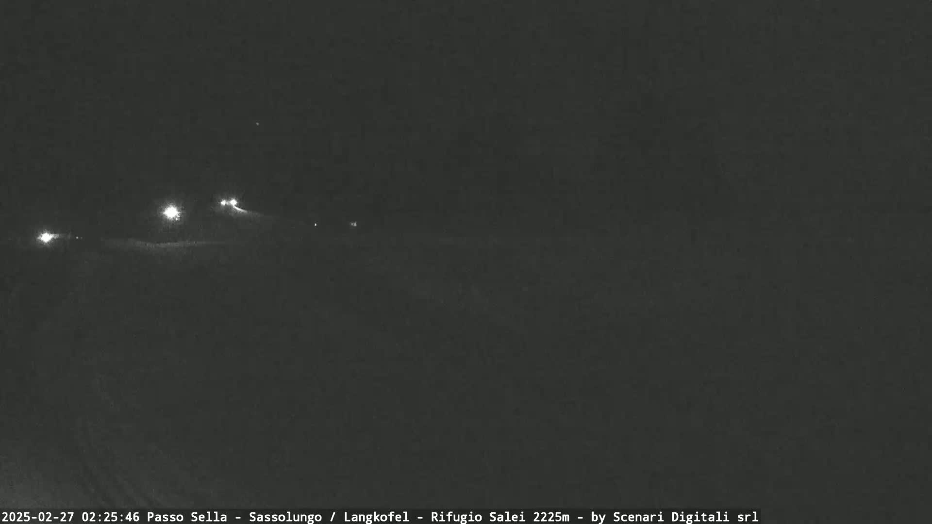 A nighttime, low-light view of a road with several sets of vehicle headlights visible in the distance.