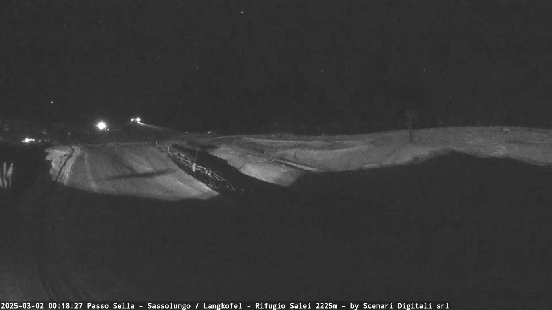 A nighttime view of a snow-covered landscape, with a road visible in the distance.