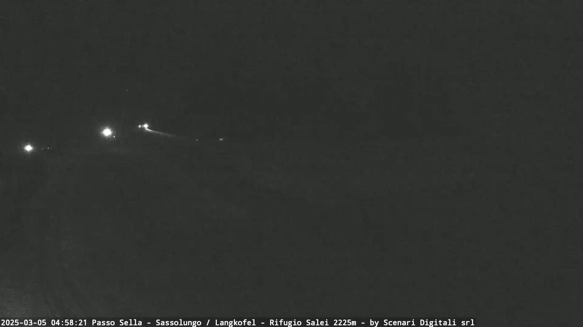 At night, a few small lights are visible in the distance on a dark, possibly mountainous landscape.