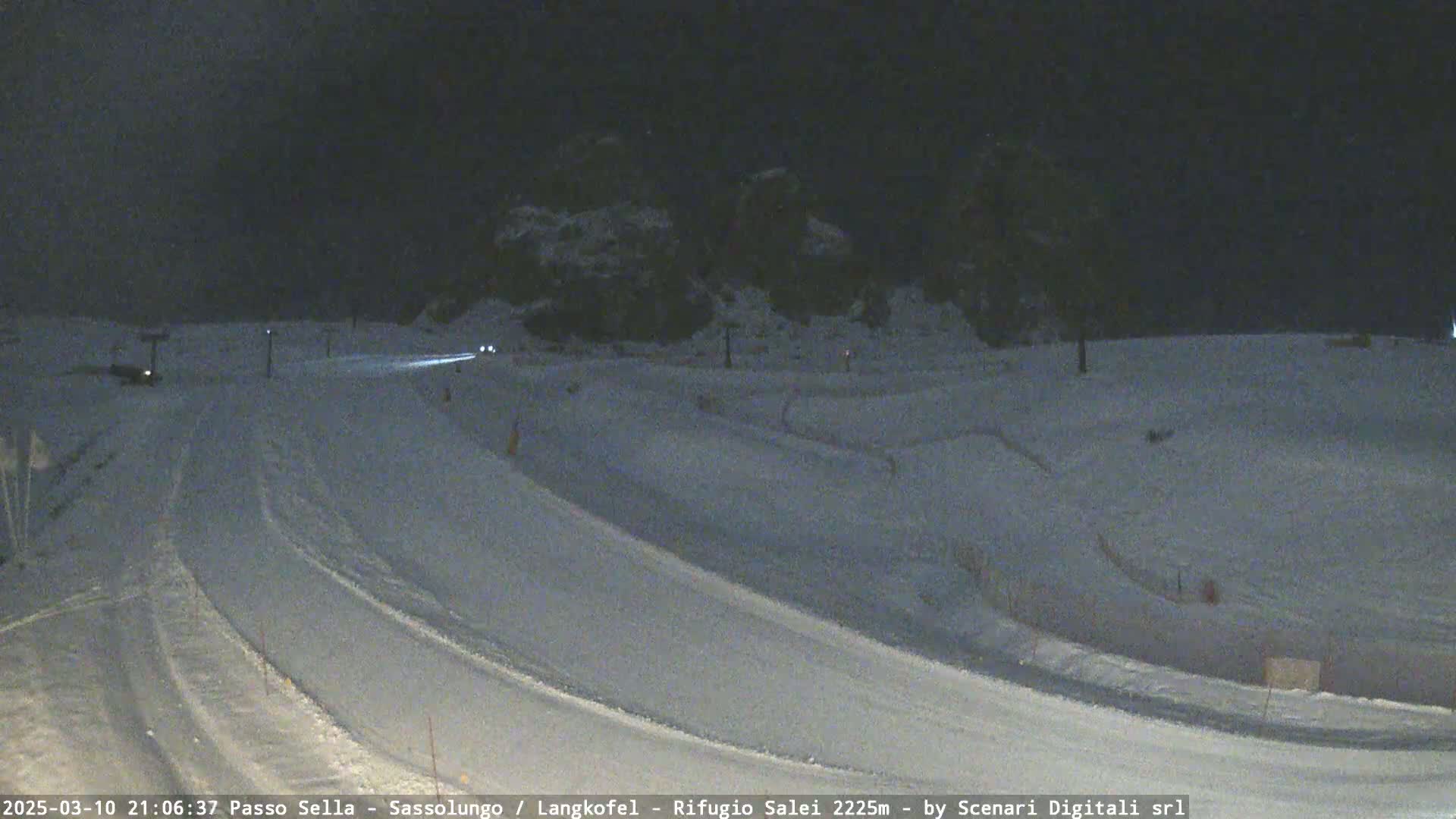 A snow-covered road curves through a nighttime landscape under a dark sky.