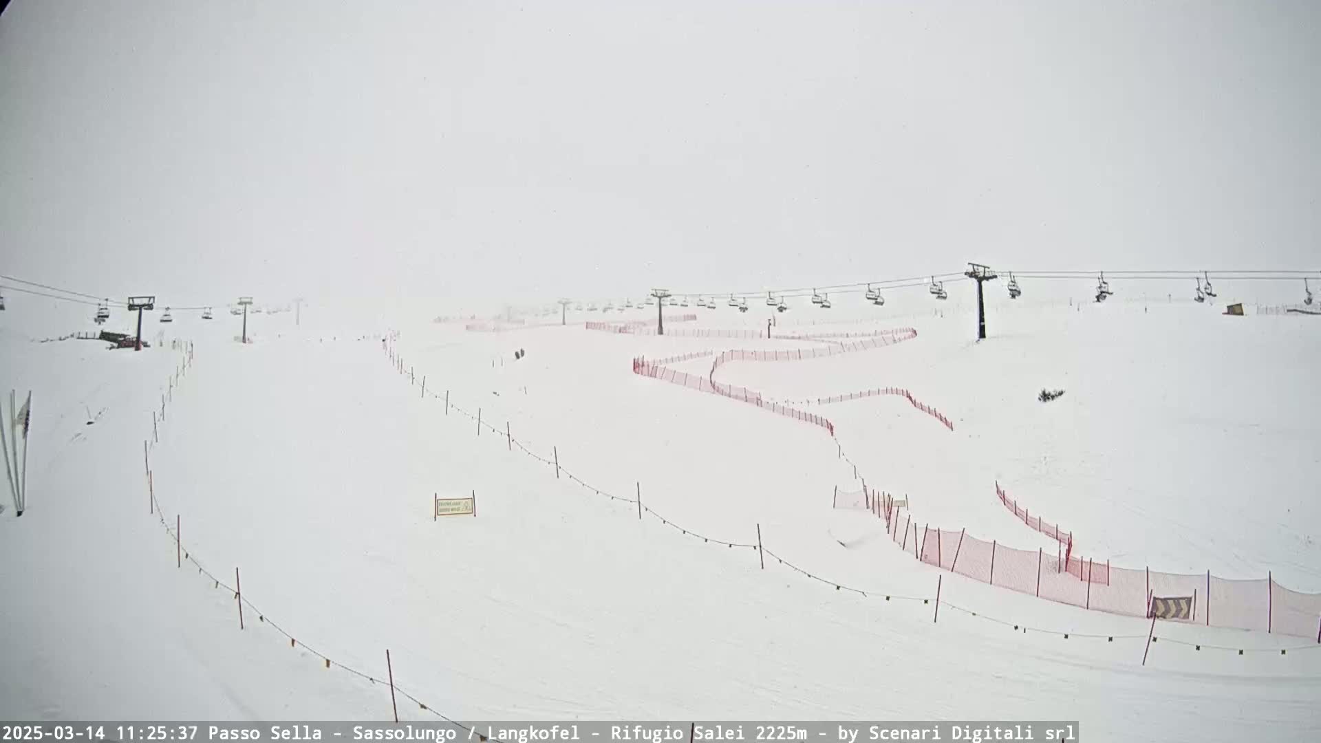 A snow-covered ski slope with chairlifts and red safety nets is visible in heavy snow.