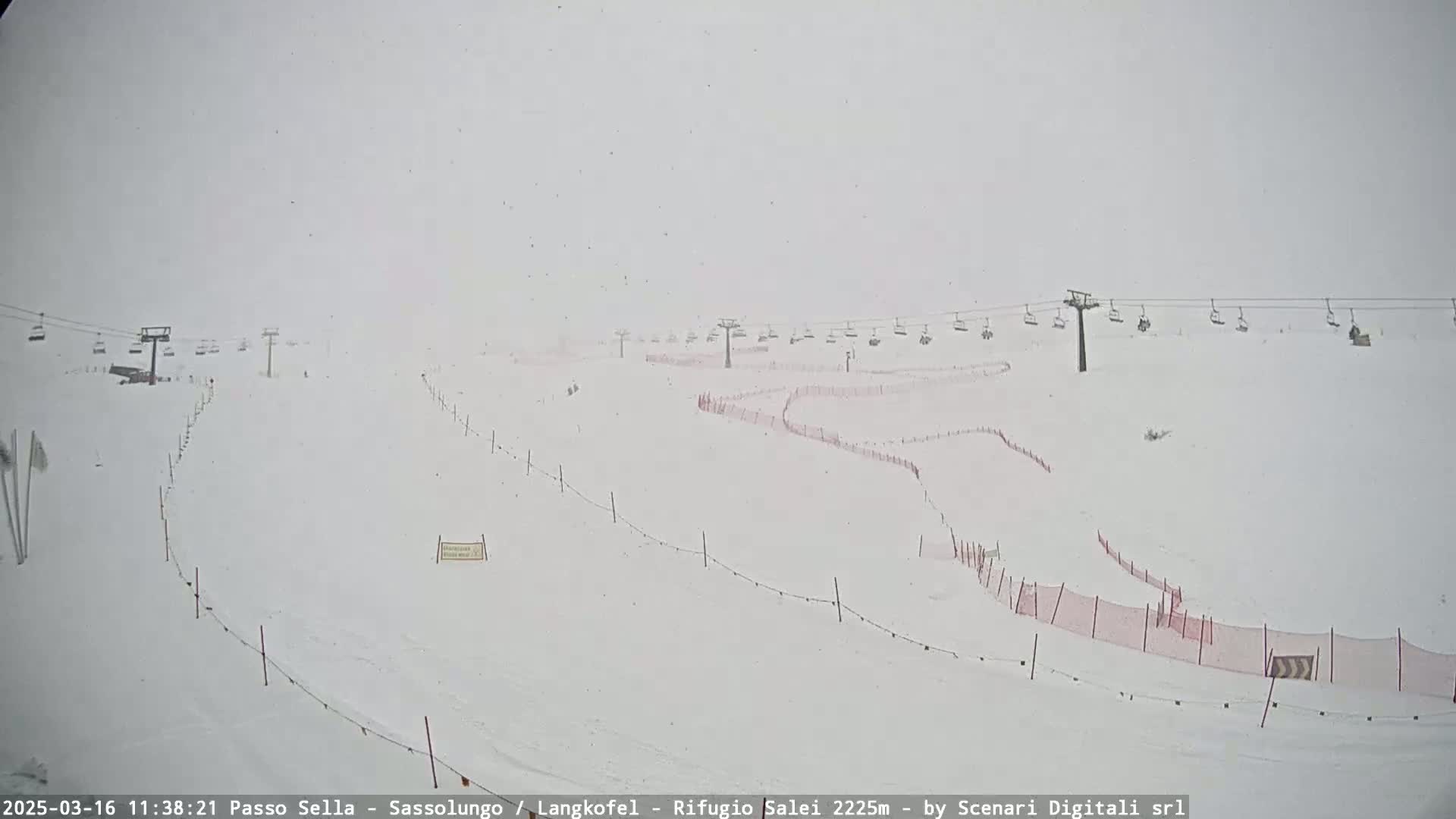 A snow-covered ski slope with chairlifts and safety netting is visible in heavy snowfall.