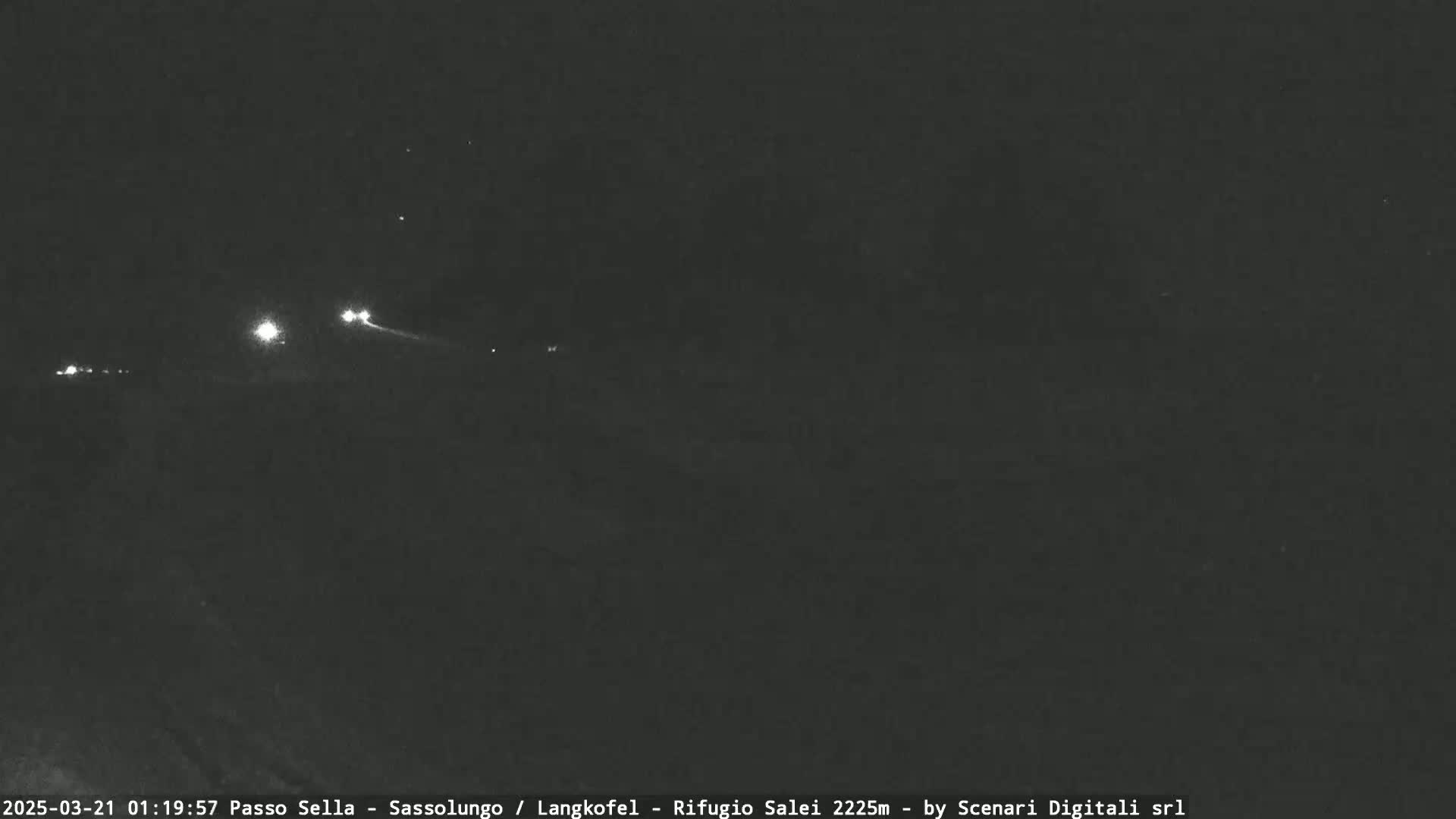 At night, a dark roadway is visible with a few distant headlights.