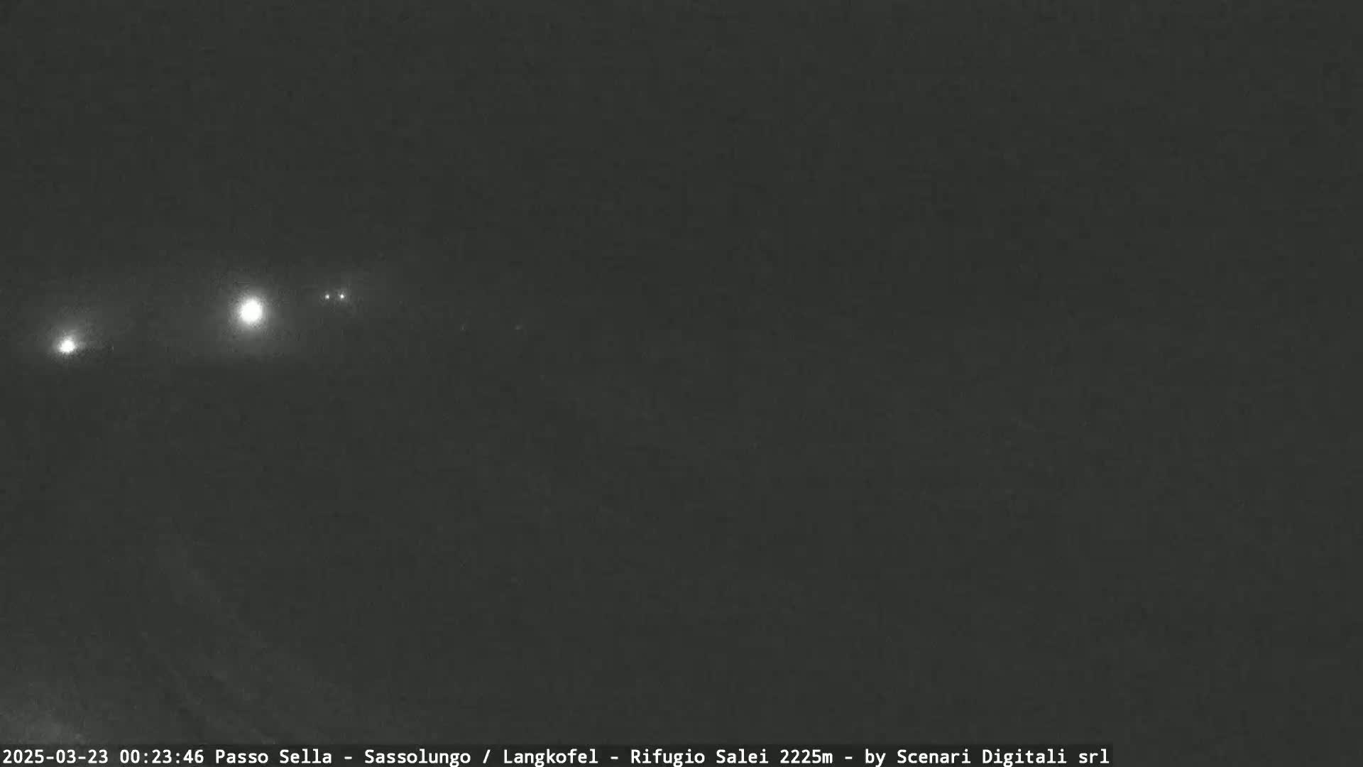 A dark, nighttime scene shows a few distant lights in the hazy atmosphere.