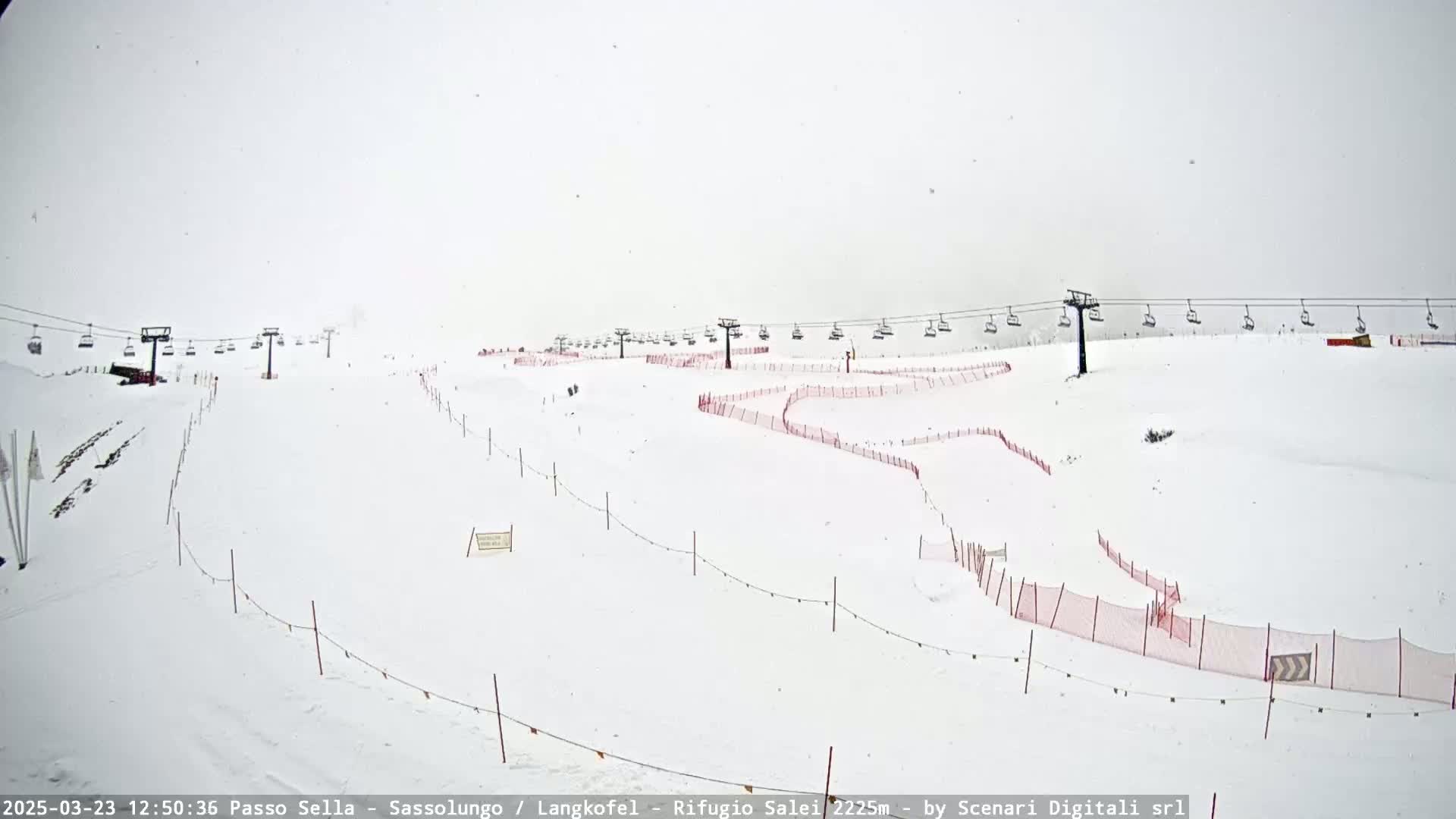A snowy ski slope with chairlifts and red safety netting is visible under heavy snowfall.