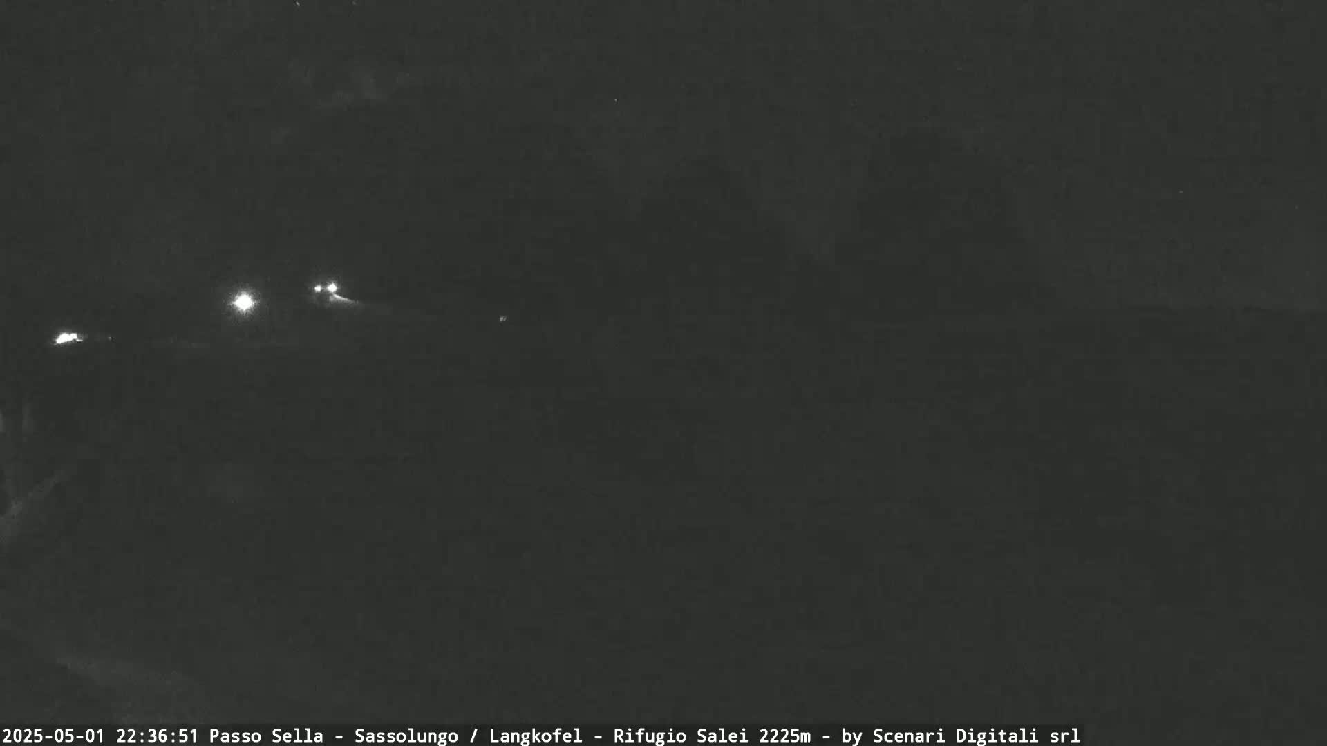 A nighttime long shot shows a dark road with a few vehicle headlights visible in the distance.