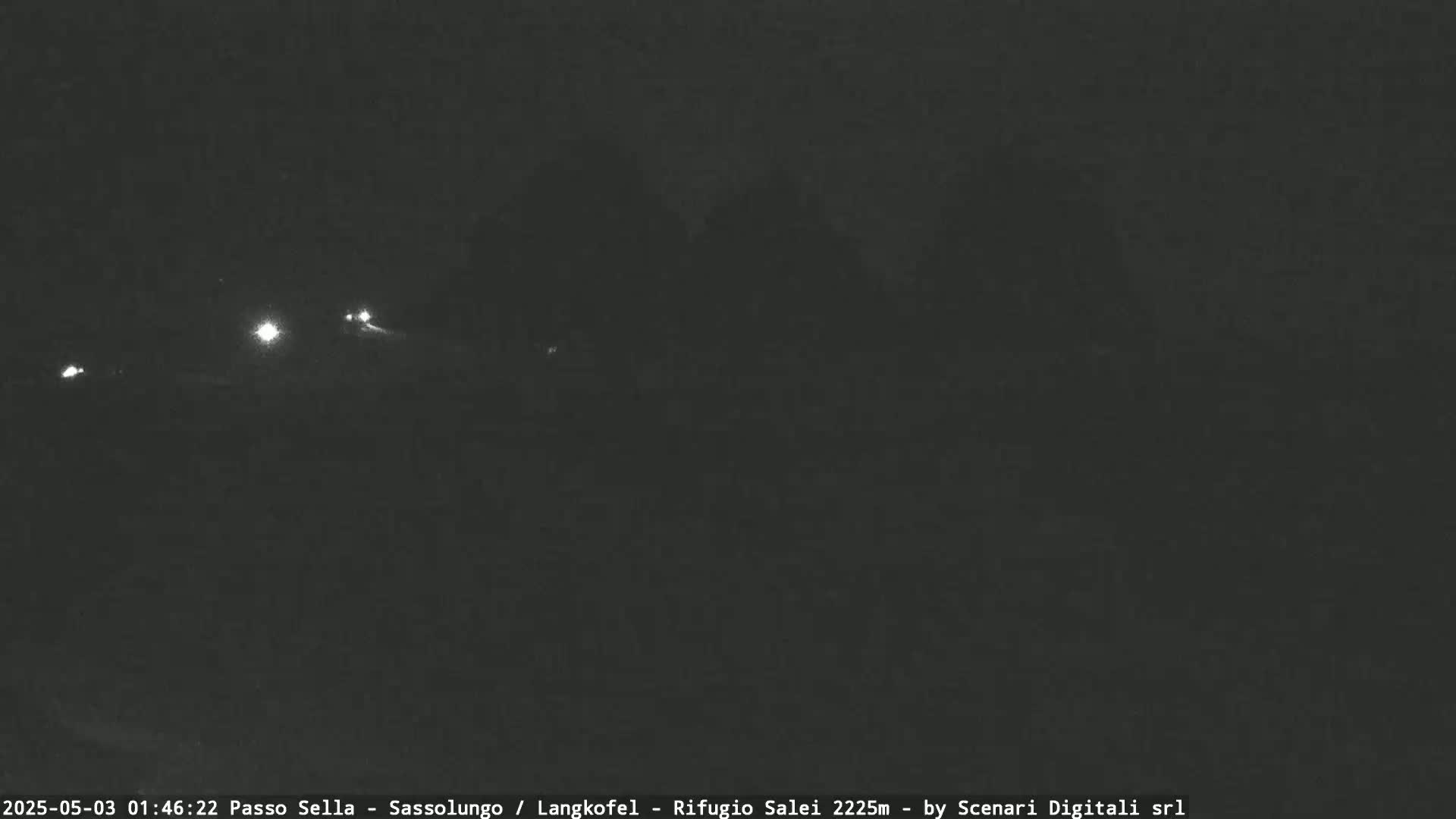 At night, several sets of vehicle headlights are visible in the distance on a dark road.