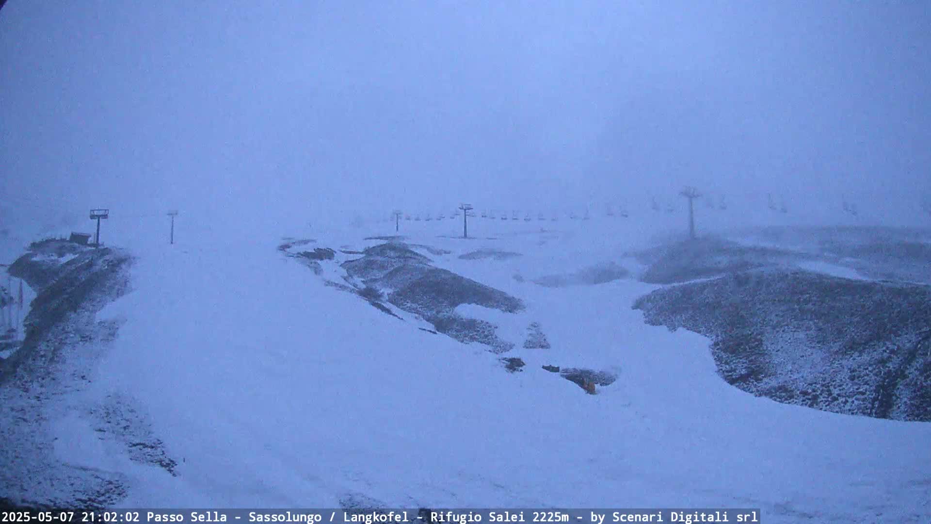 A snow-covered ski slope with several chairlifts is visible in a heavy snowstorm.