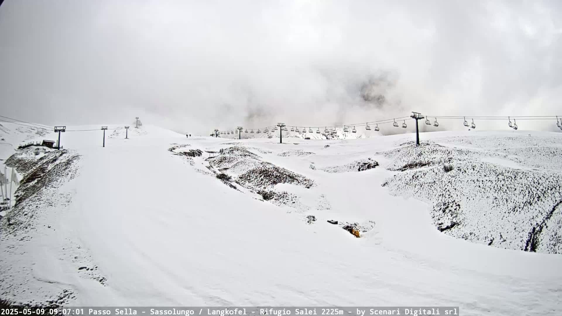 A snow-covered ski slope with a chairlift stretches across the scene under a foggy sky.