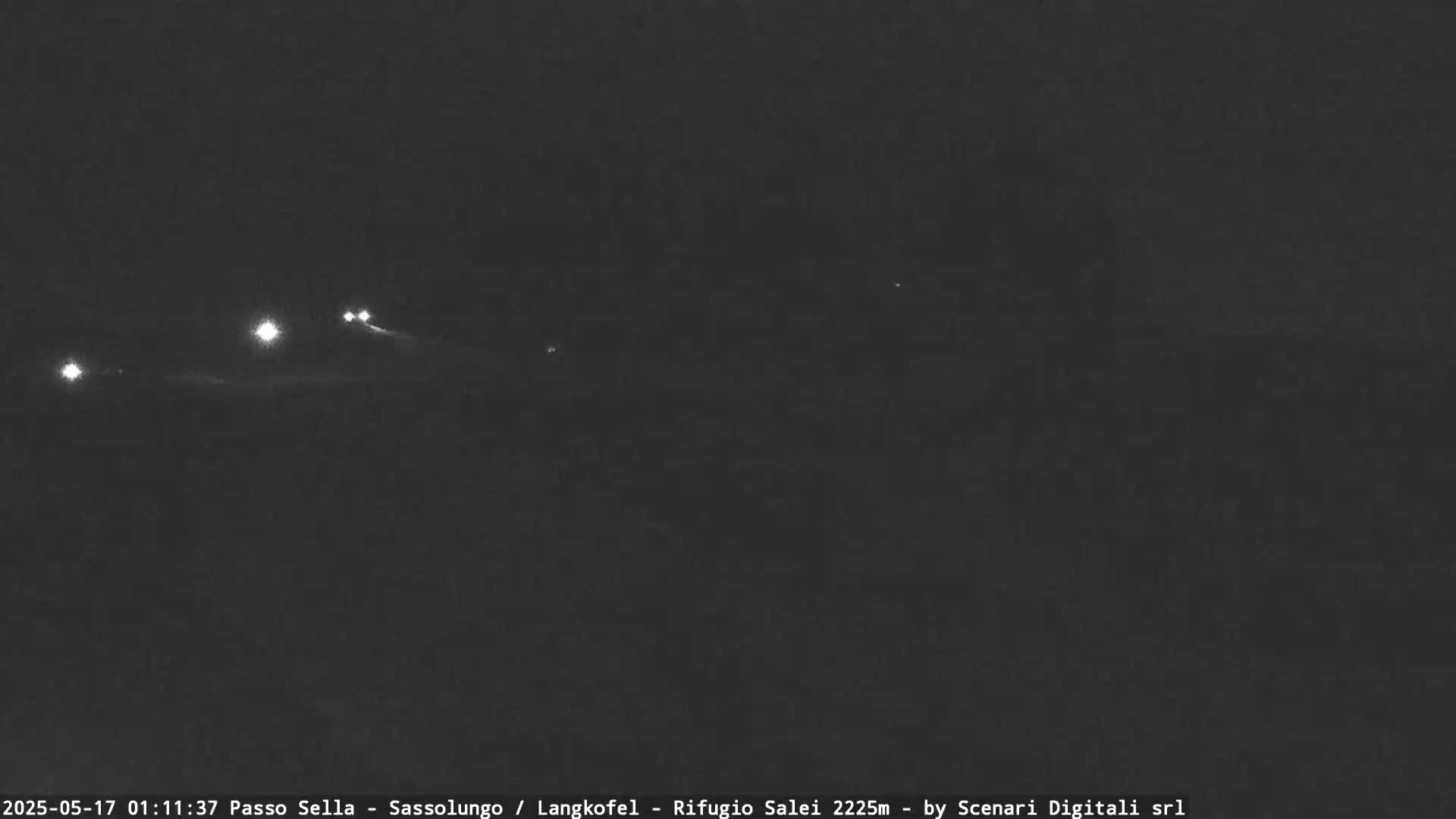 Several sets of vehicle headlights are visible in the distance on a dark, nighttime road.