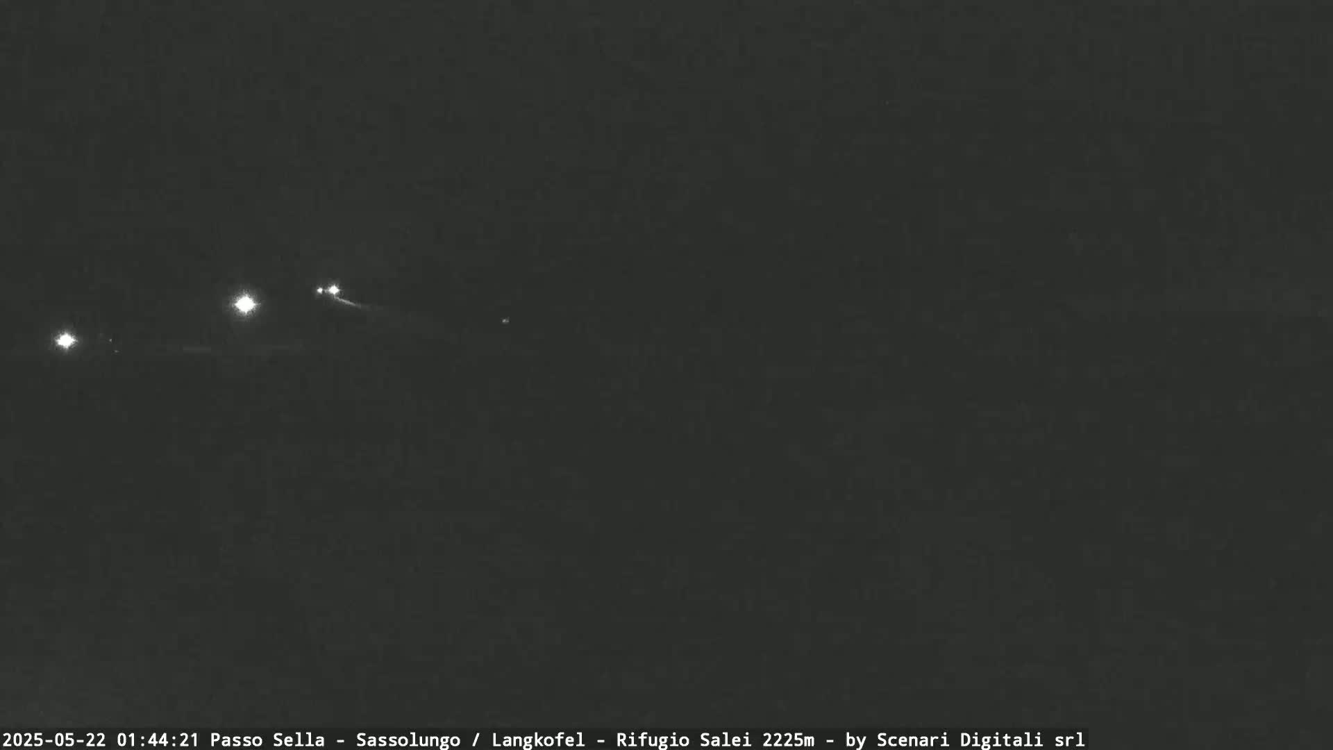 At night, several small lights are visible in the distance against a dark sky.