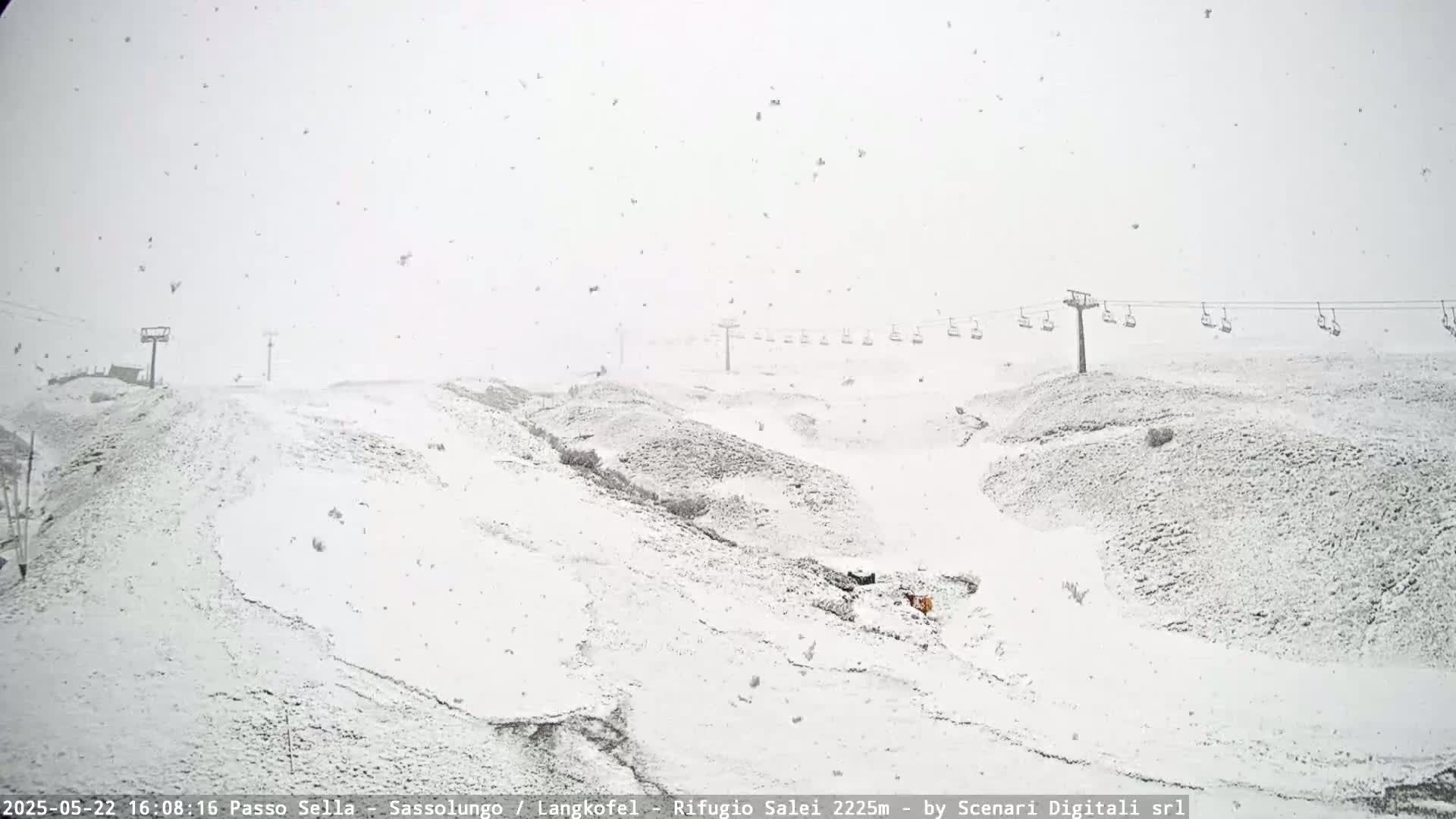 A snow-covered landscape with a chairlift in the background during a heavy snowfall.