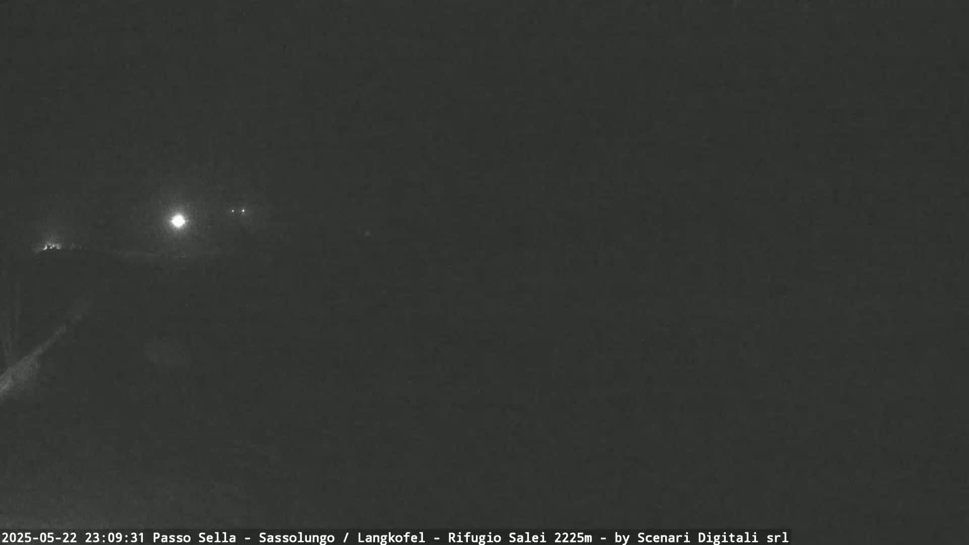 A dark, nighttime scene shows a few distant lights in the background under a dark sky.