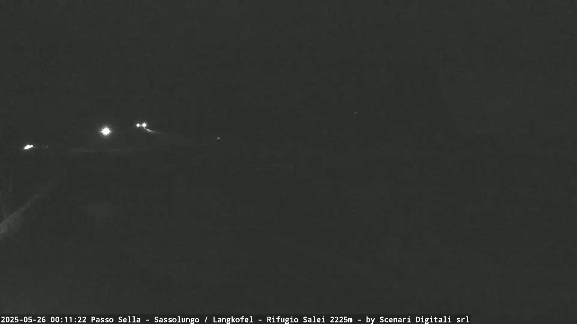 At night, a dark road is visible with a few sets of vehicle headlights in the distance.