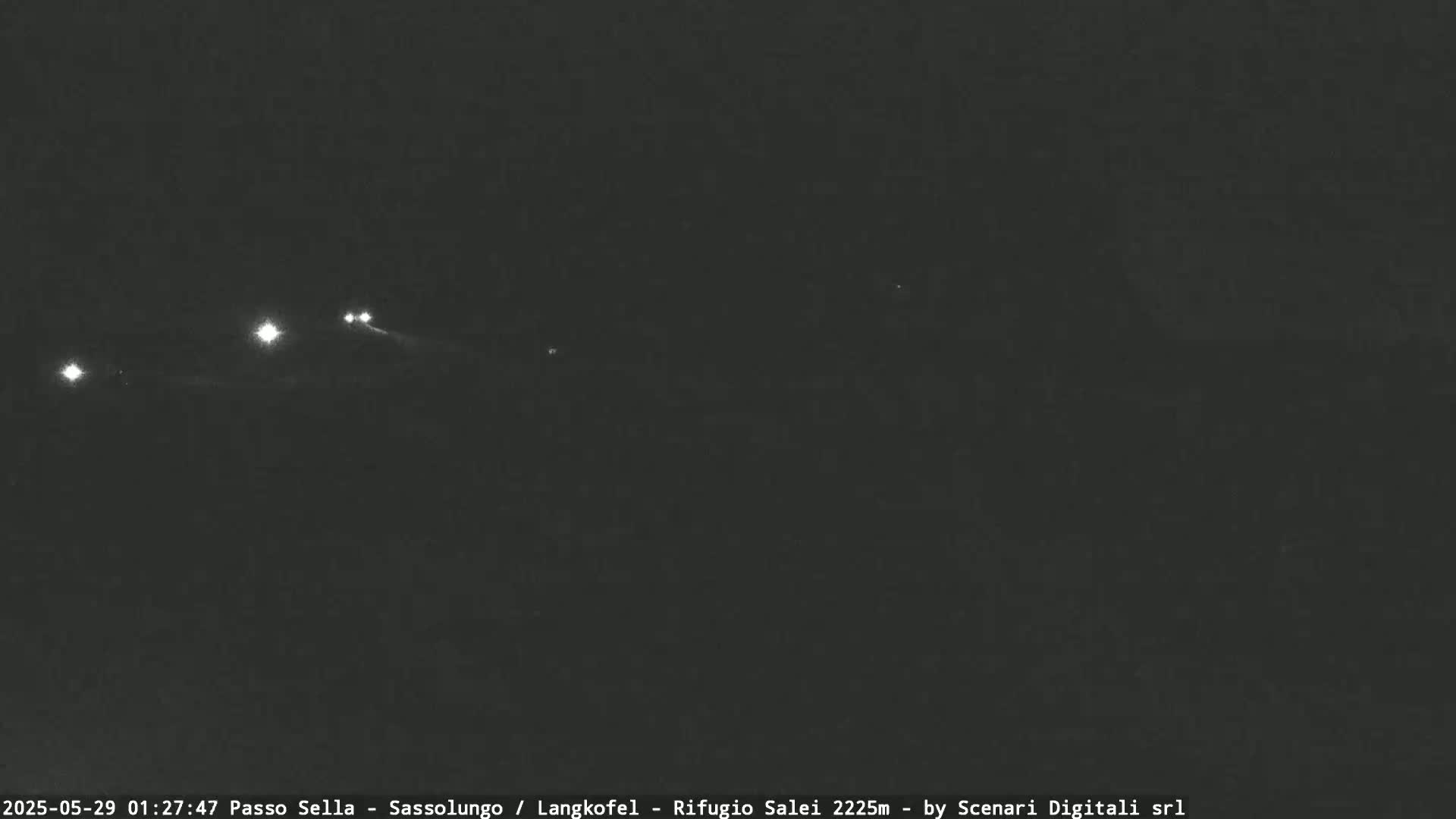 At night, several sets of vehicle headlights are visible in the distance on a dark road.
