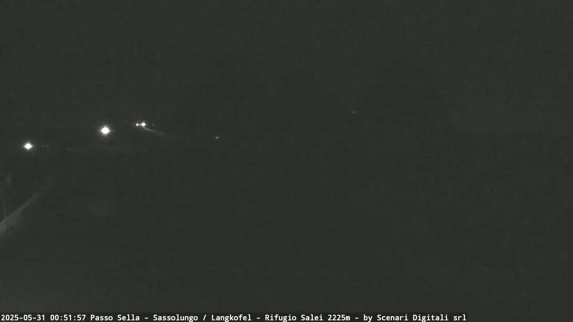 A nighttime, low-light image shows a dark road with a few distant headlights.