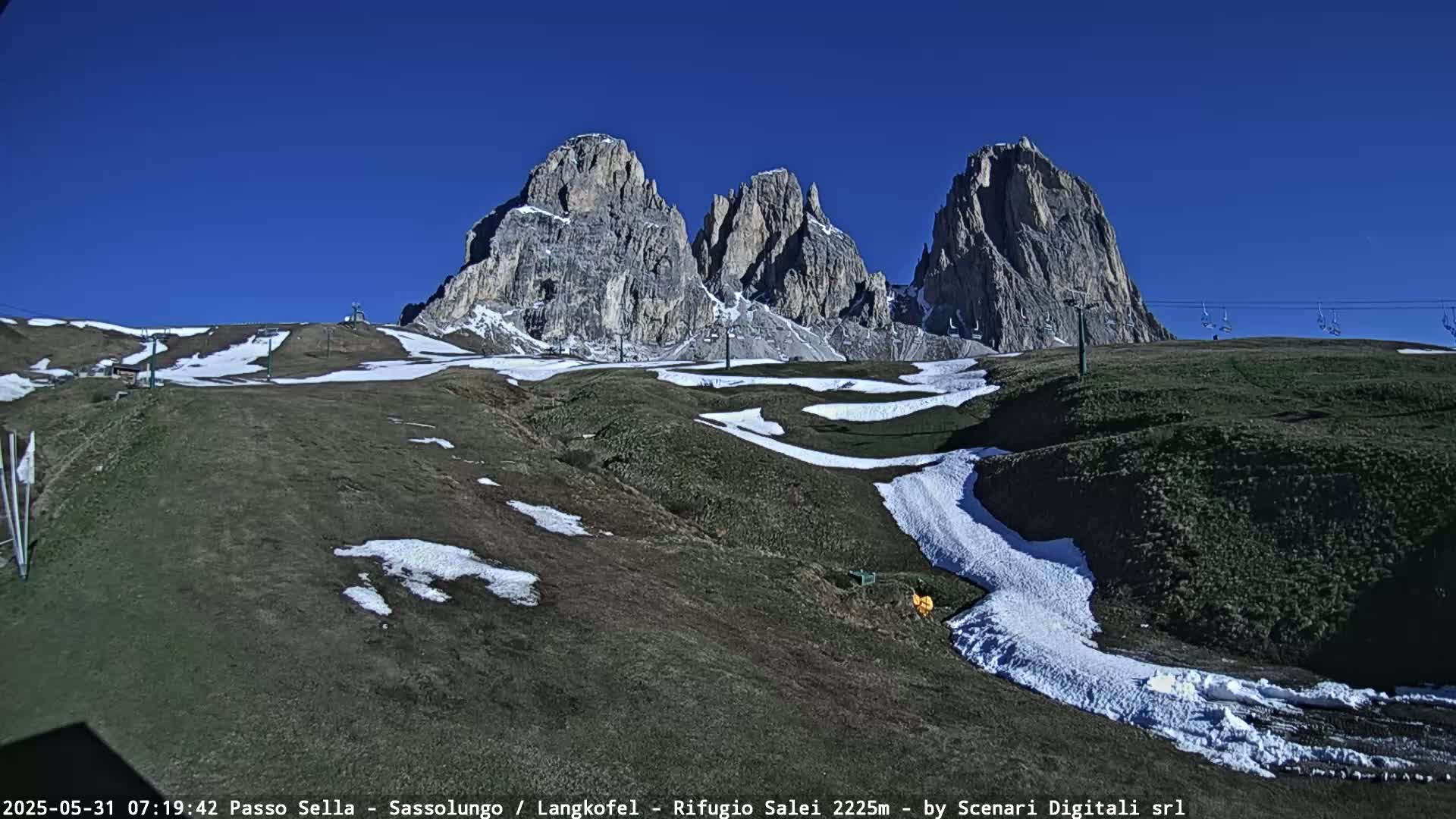 A mountain range with snow patches on the lower slopes under a clear blue sky.