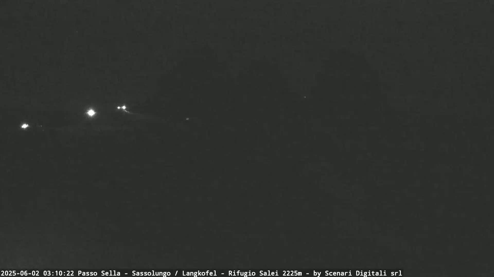At night, several sets of headlights from vehicles are visible in the distance on a dark road.