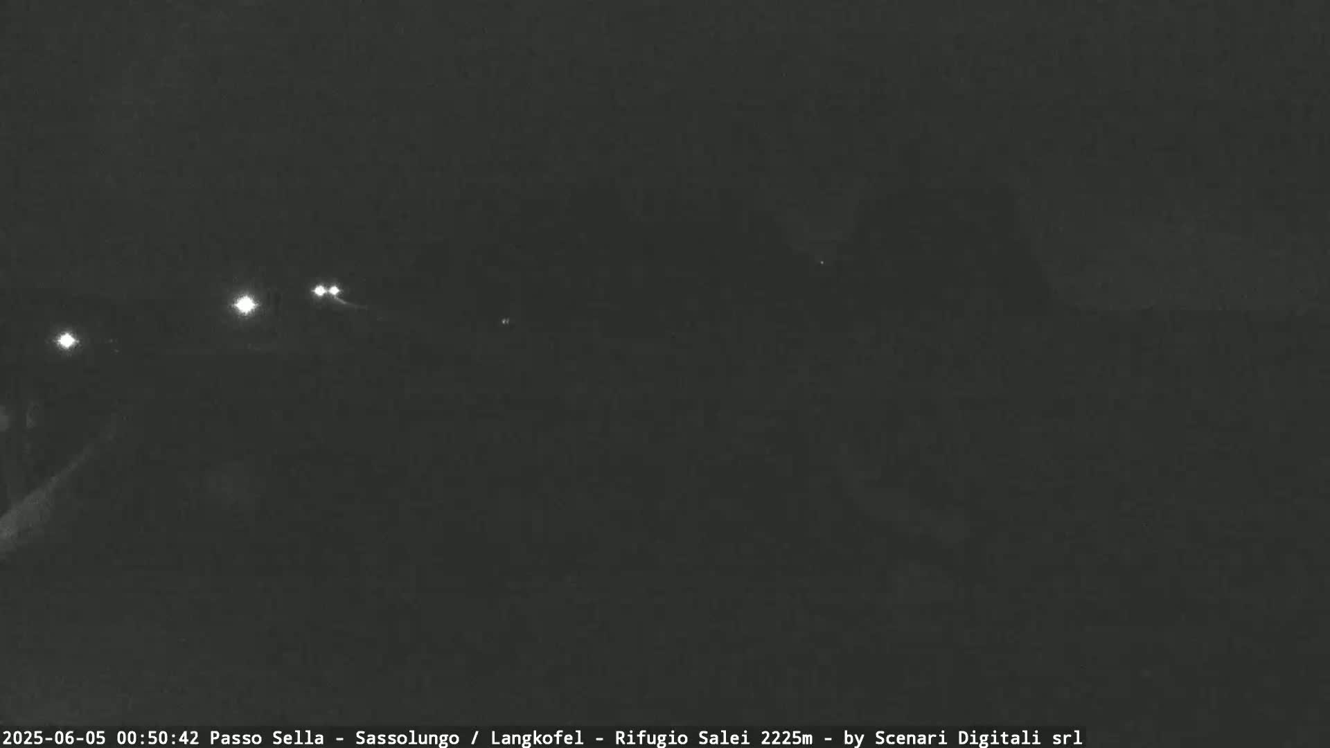 At night, several sets of vehicle headlights are visible in the distance on a dark road.