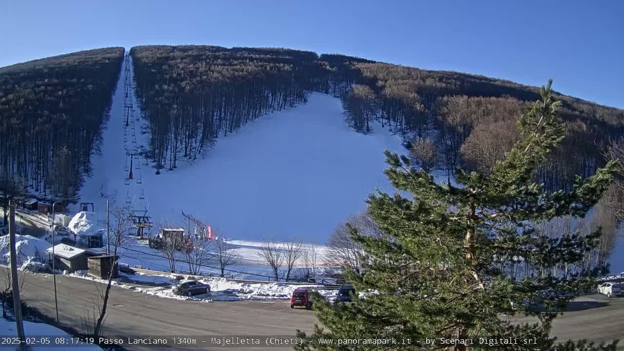 A ski slope on a snow-covered mountain with a chairlift visible under a clear blue sky.