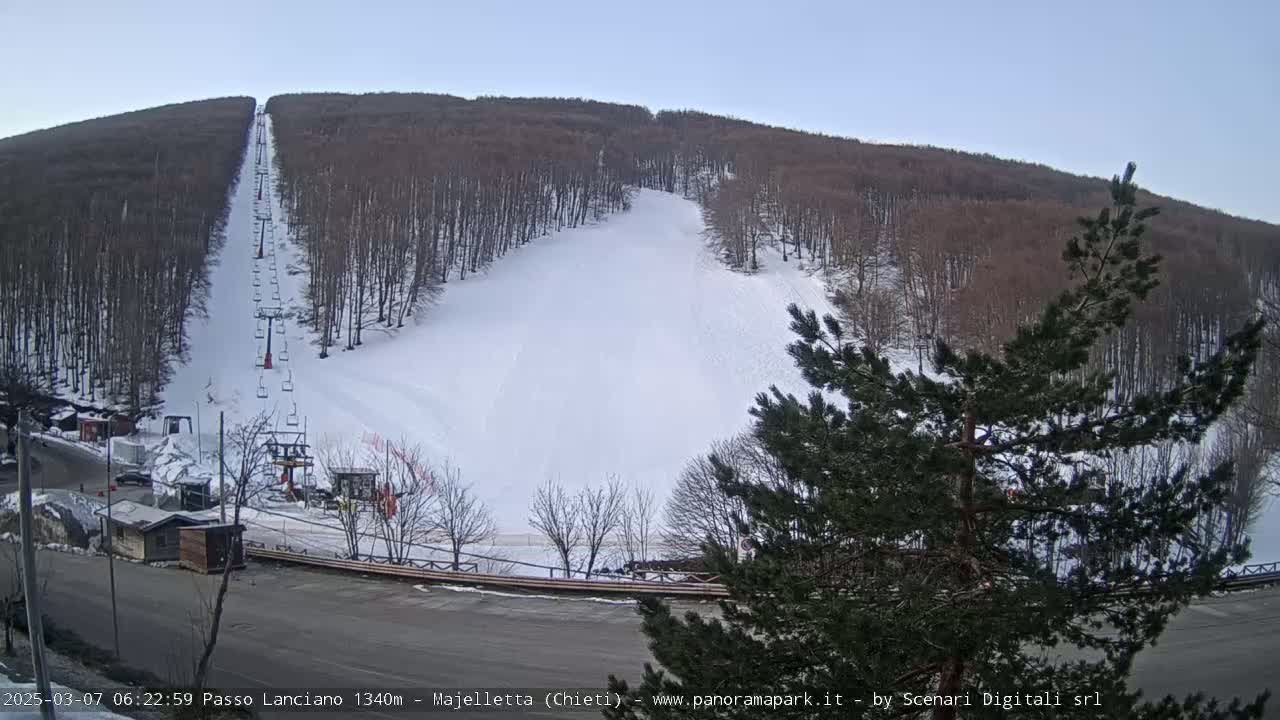 A ski slope with a chairlift is visible on a snow-covered hillside under a clear sky.