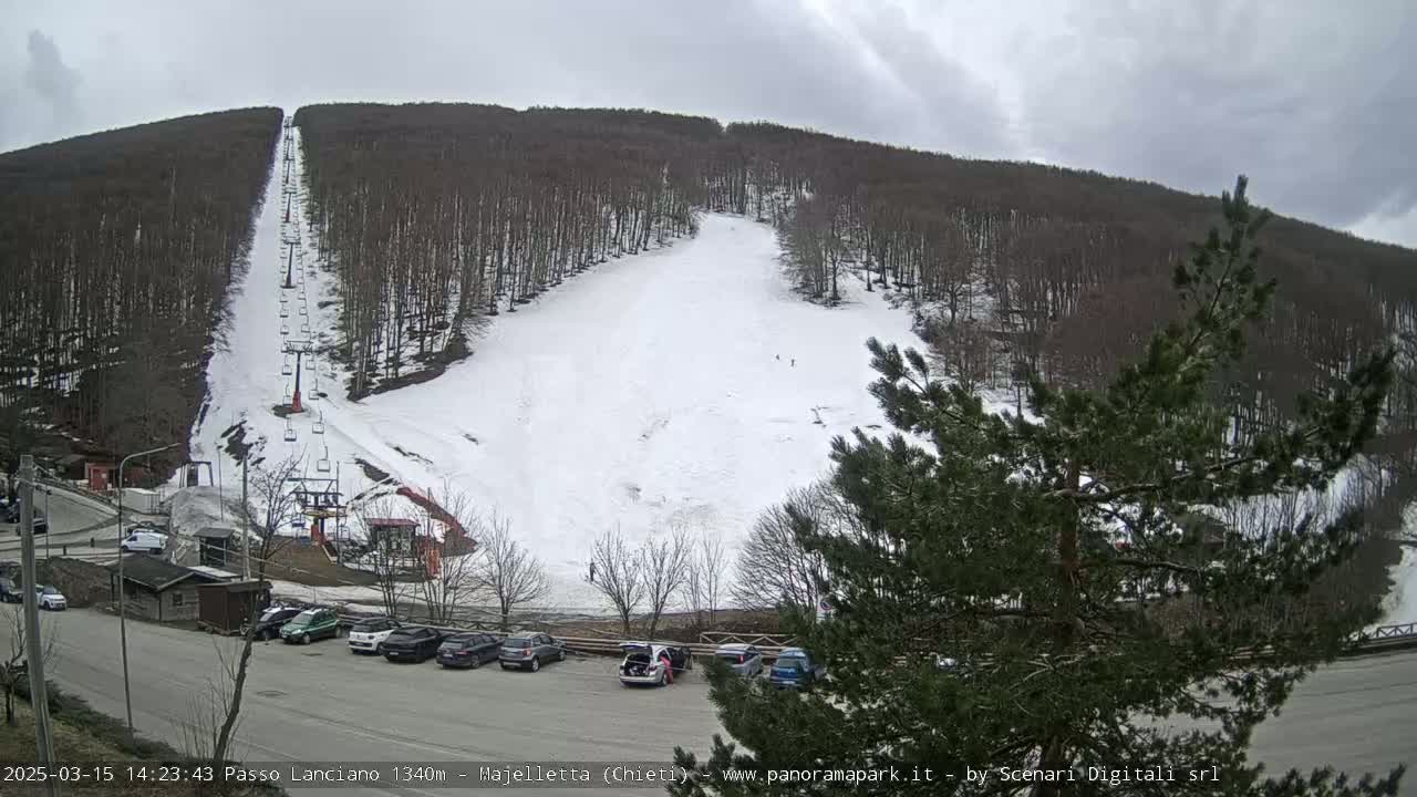 A ski slope with a chairlift is visible on a snow-covered hillside under an overcast sky.