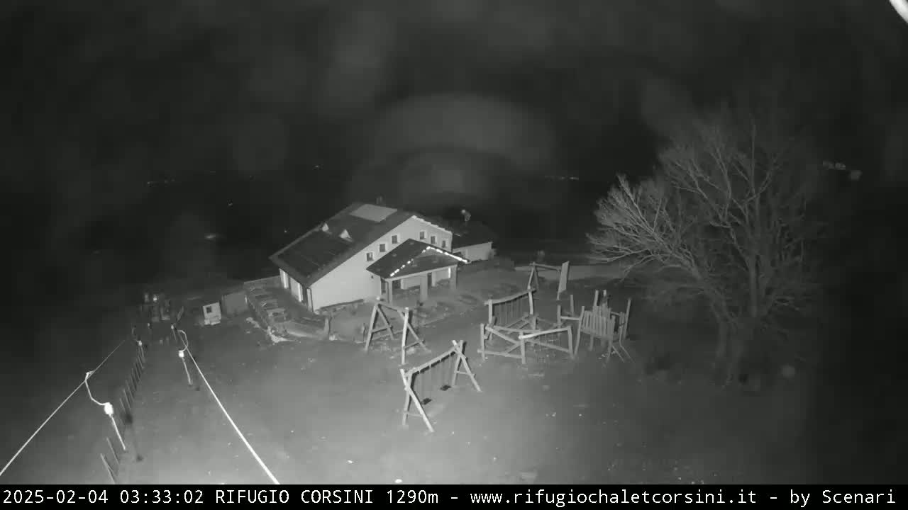 A nighttime, black and white image shows a building with a playground next to it, under a dark sky.