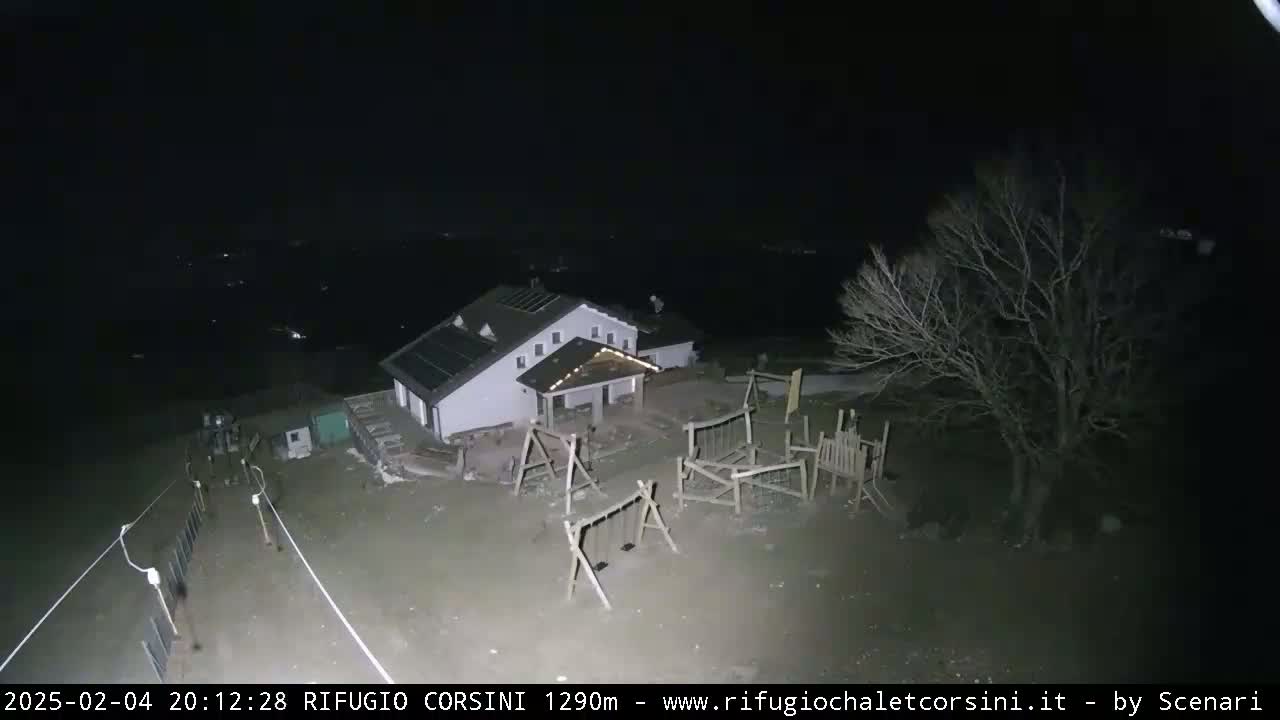 A building with a playground is visible at night under a dark sky.