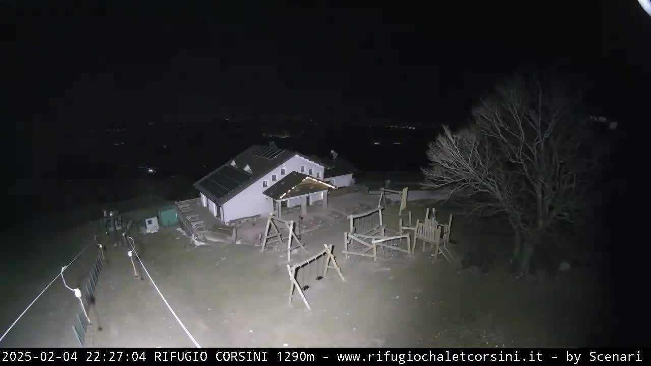 A nighttime aerial view shows a building with a playground next to it, under a clear, dark sky.
