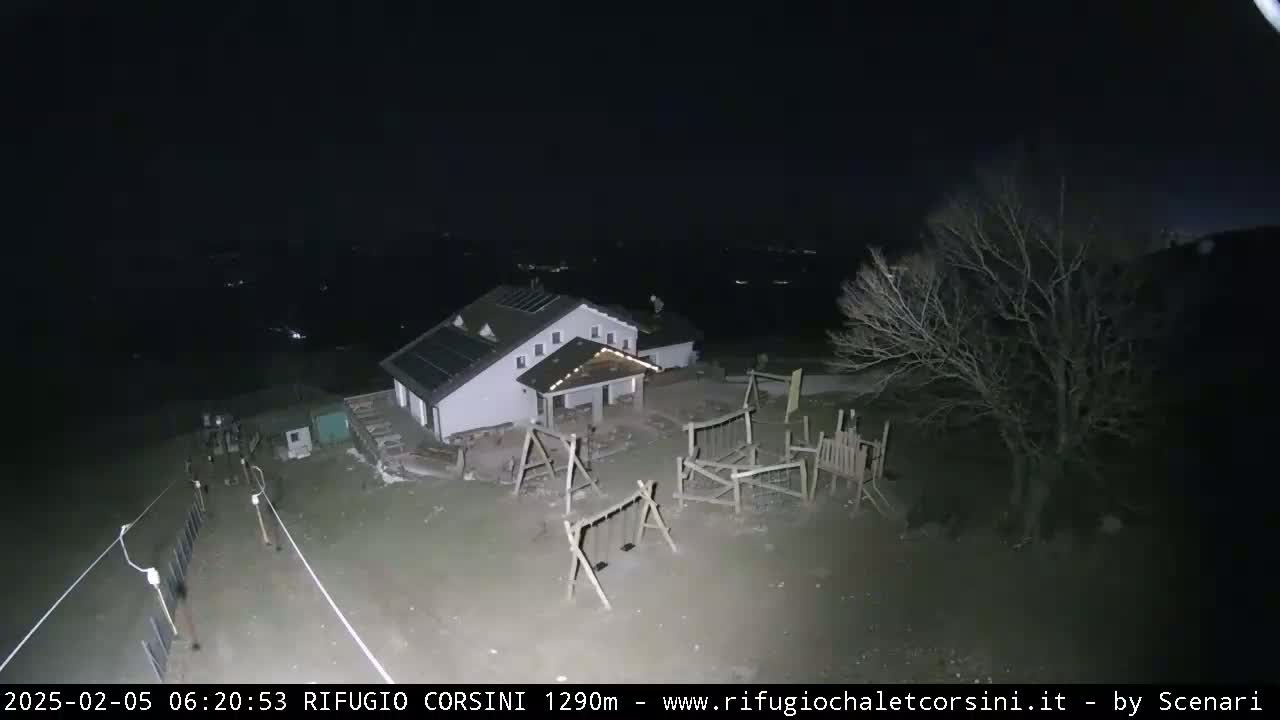 A nighttime aerial view shows a building with a playground next to it, under a clear, dark sky.