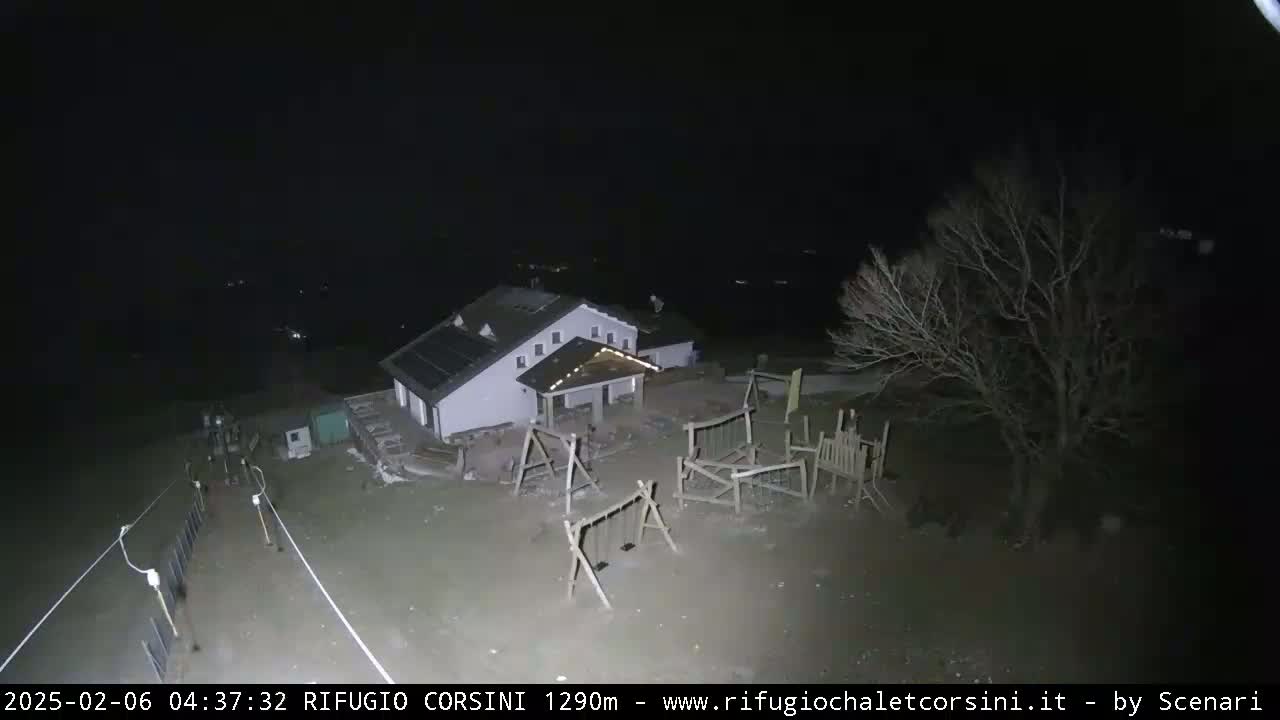 A nighttime, overhead view shows a building with a playground and a few bare trees under a dark sky.