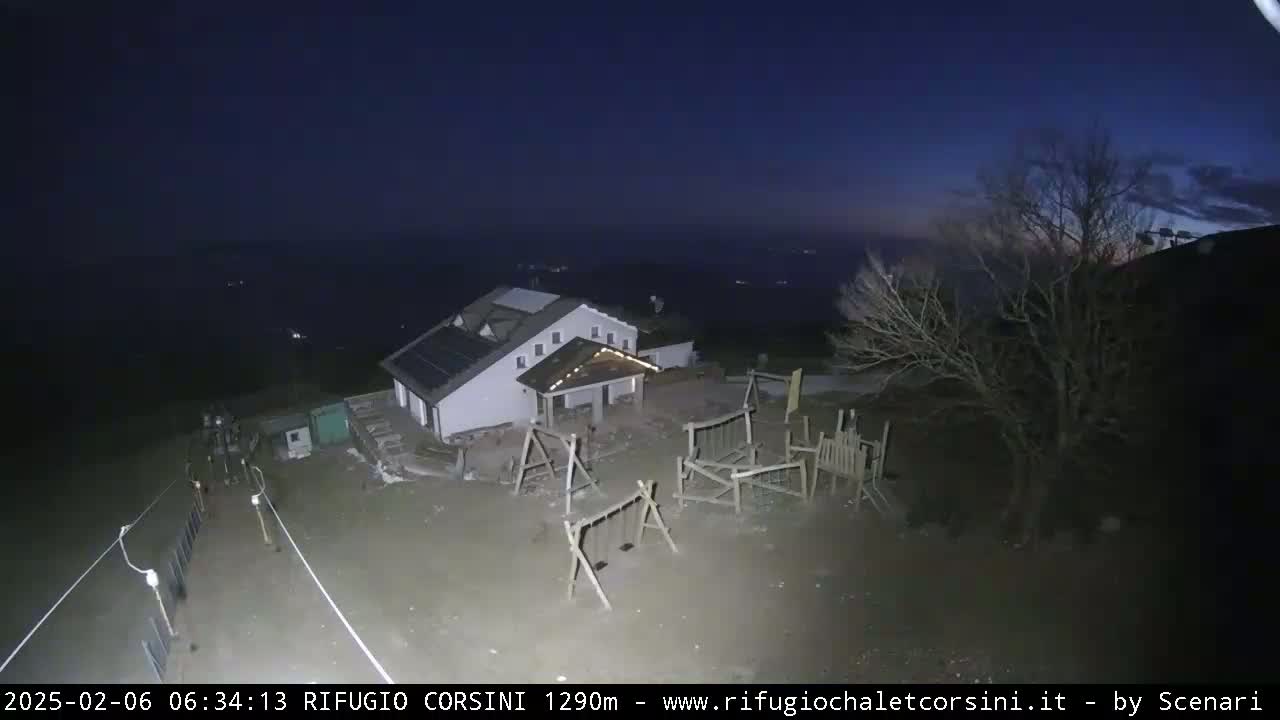 A building with a playground sits on a hilltop at night under a dark, clear sky.