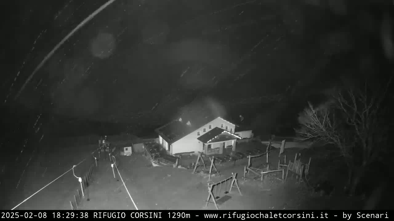 A nighttime, snowy scene shows a building with a playground, viewed from above.
