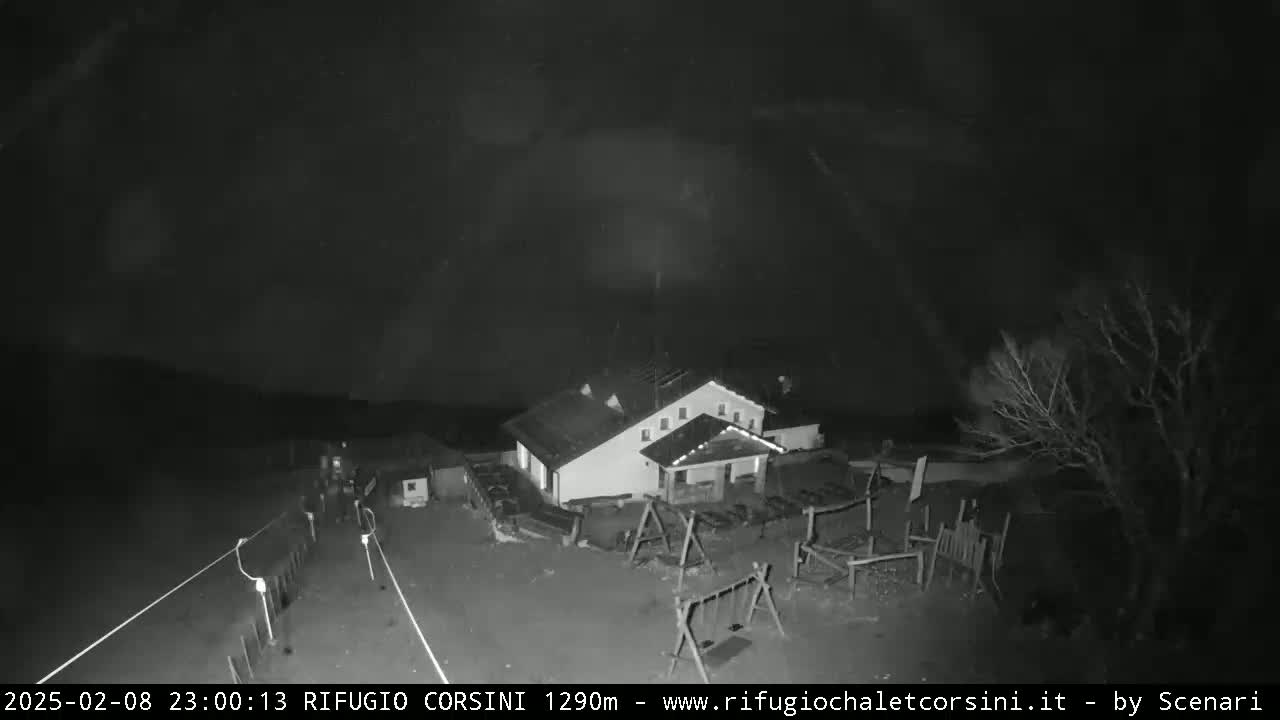 A nighttime, low-light image shows a building with a playground next to it, under a dark and cloudy sky.