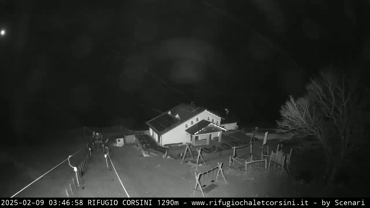 A nighttime, overhead view shows a small building with a playground next to a road under a dark, clear sky.