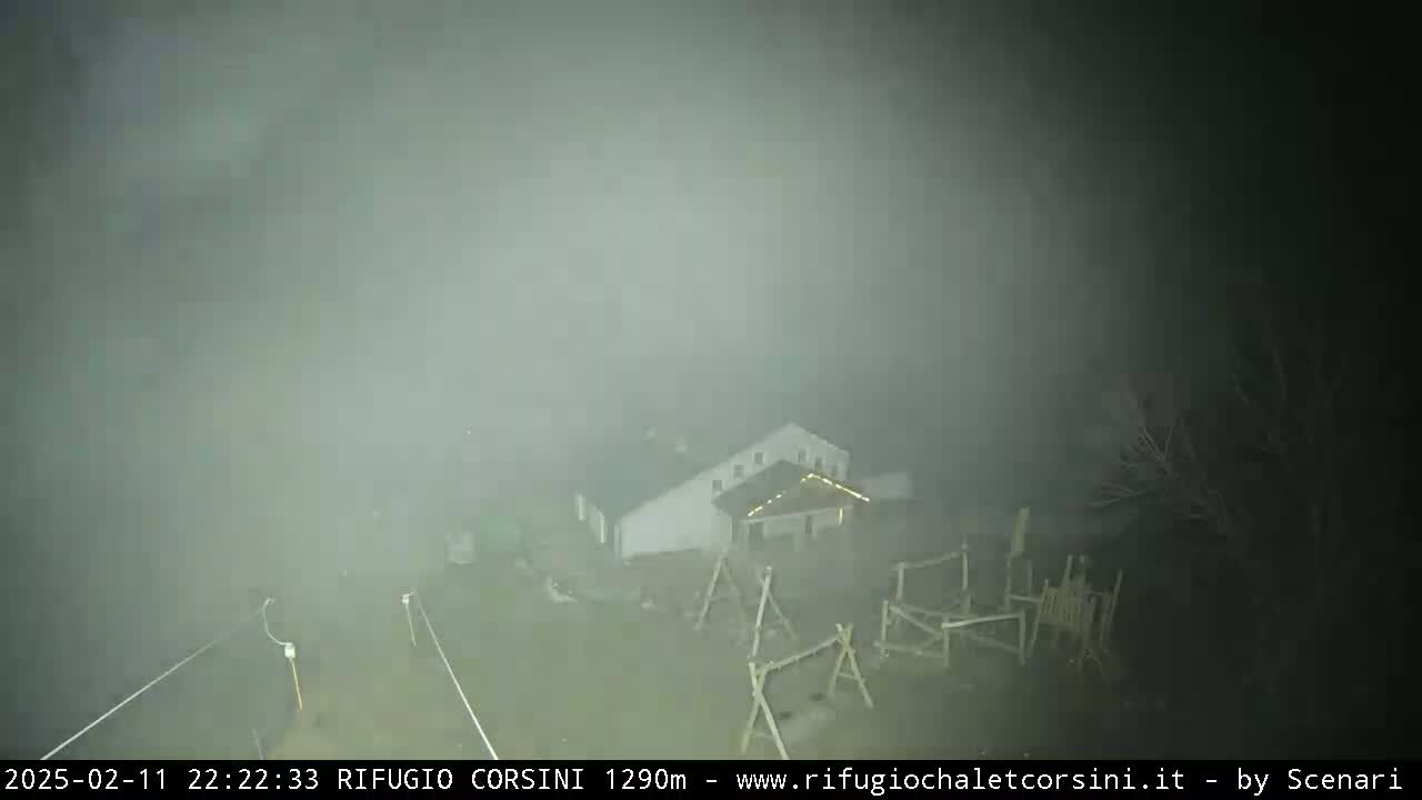 A building and playground are barely visible through a thick fog at night.