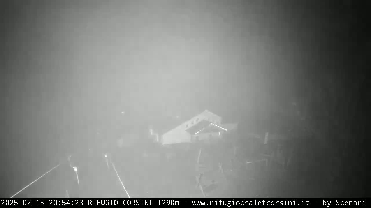 A nighttime, foggy view shows a building and a road.